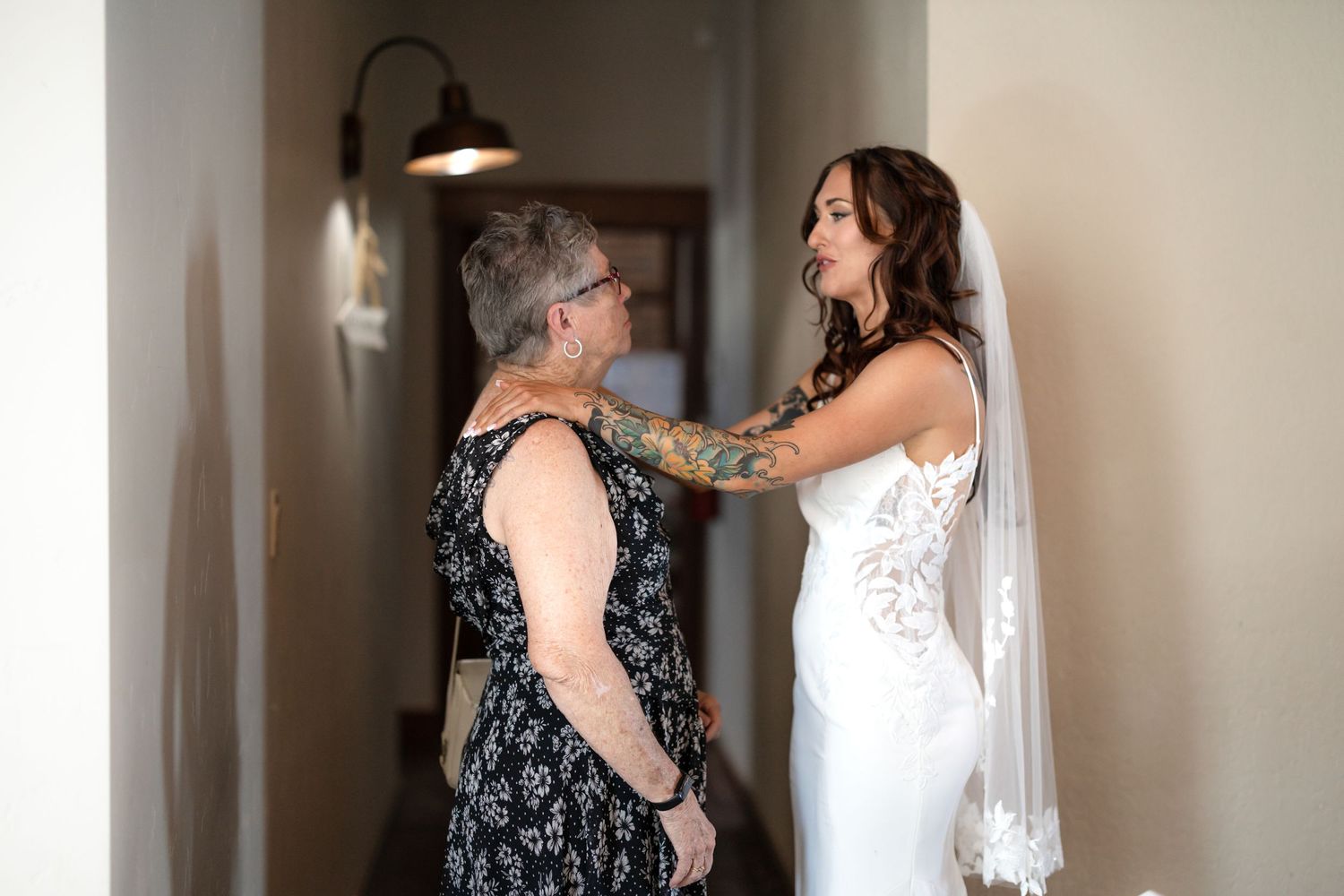 Emotional pre-wedding moment in hallway with vintage lighting fixture.