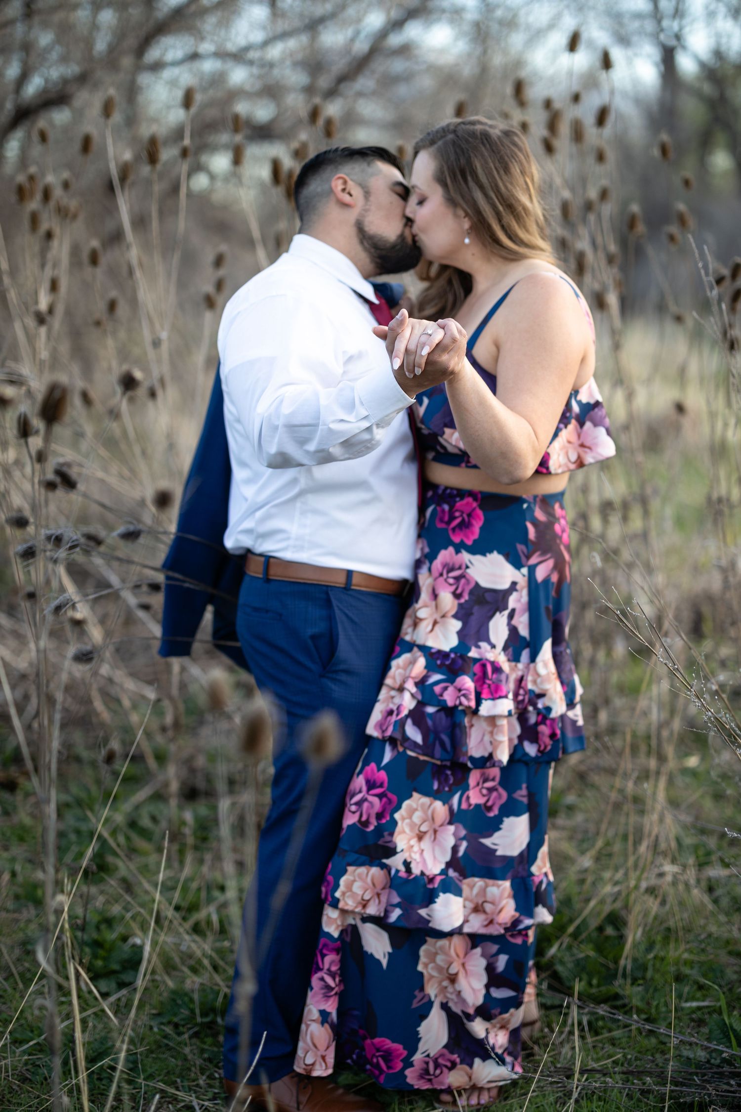 A romantic couple embraces while surrounded by dried cattails during golden hour.
