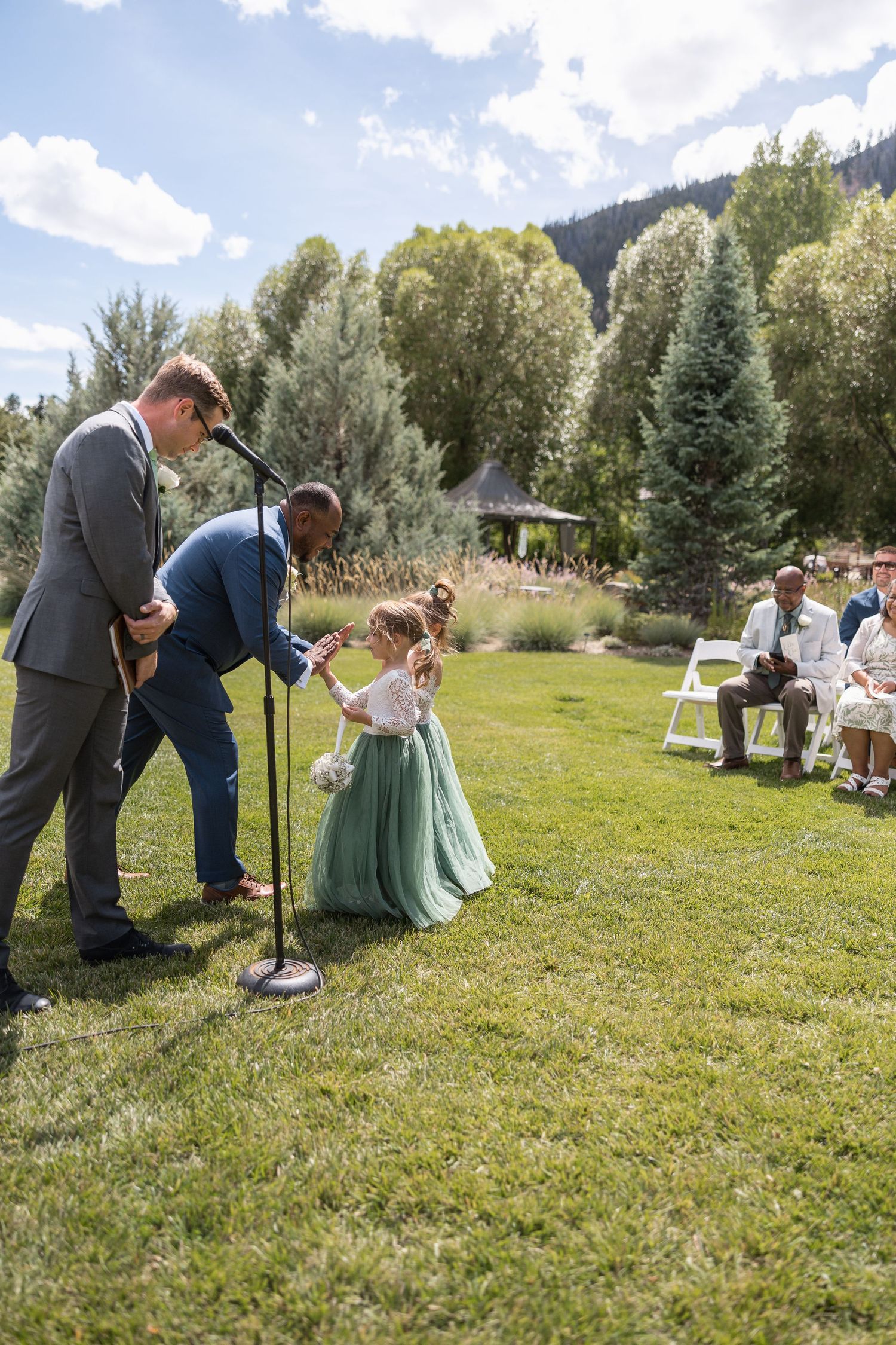 Wedding party plays outdoor lawn games during reception with mountain backdrop.