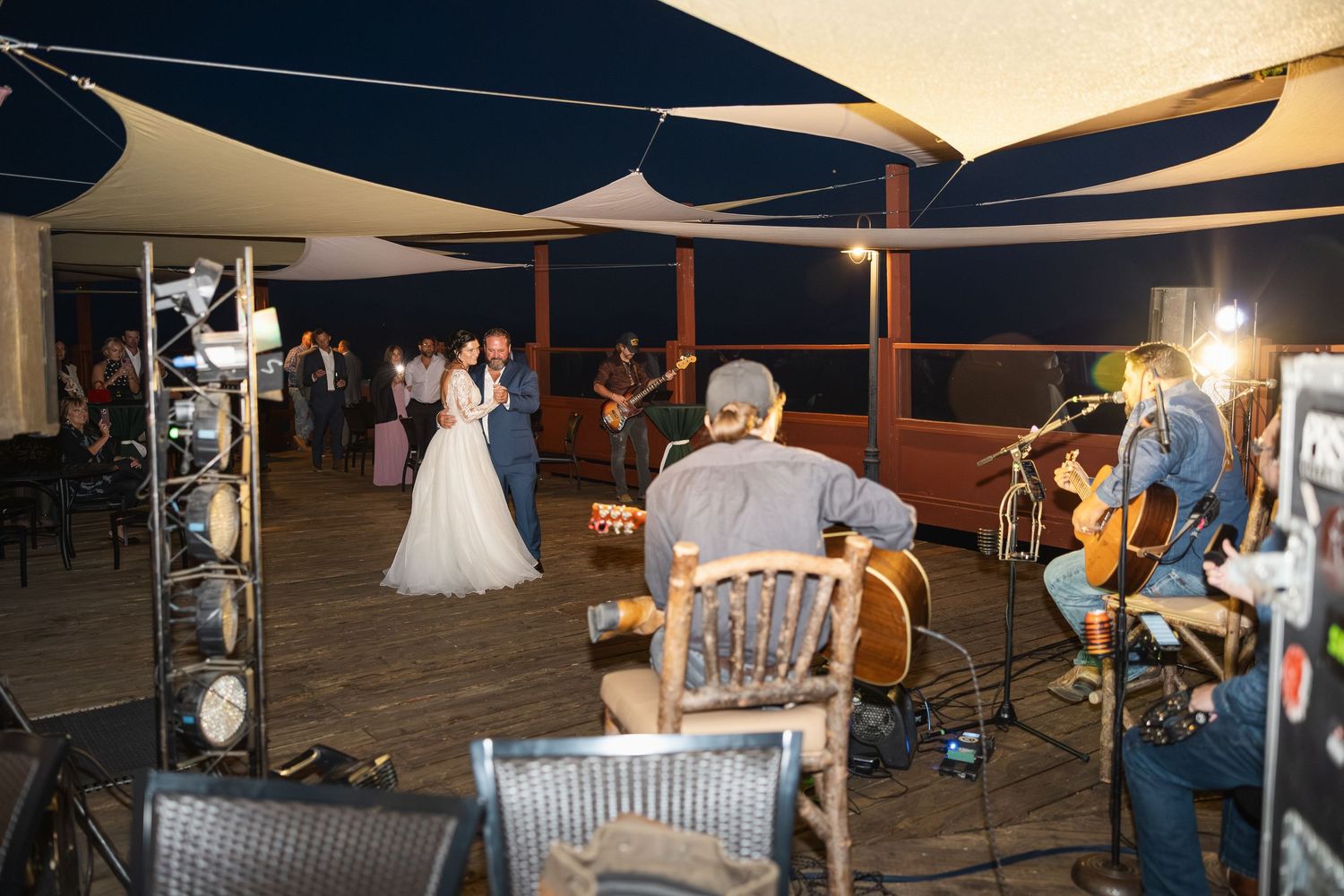 Wedding reception band performing under white canopy sails at dusk.