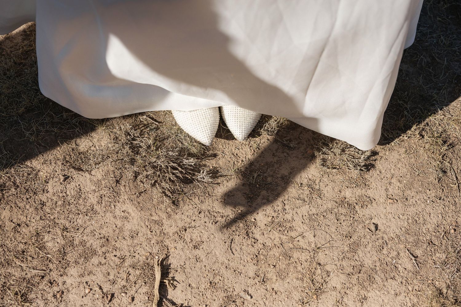 Wedding dress flowing gracefully against a desert backdrop with rugged mountains.