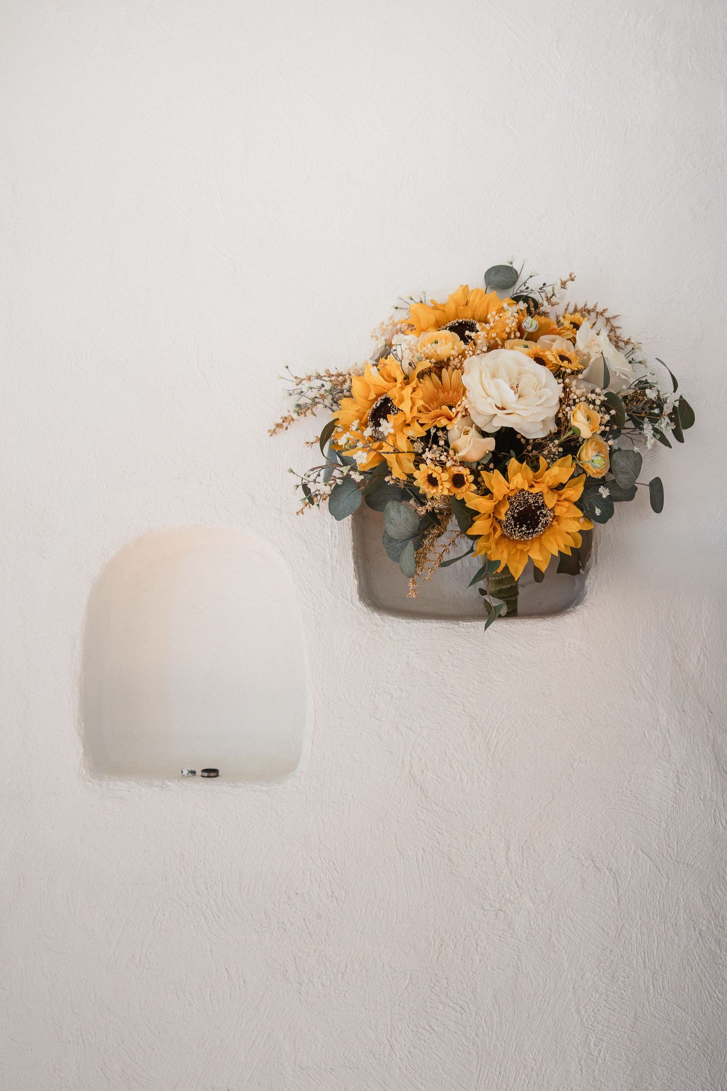 A minimalist series of white wall sconces with bright sunflower arrangements creating an elegant floral display.