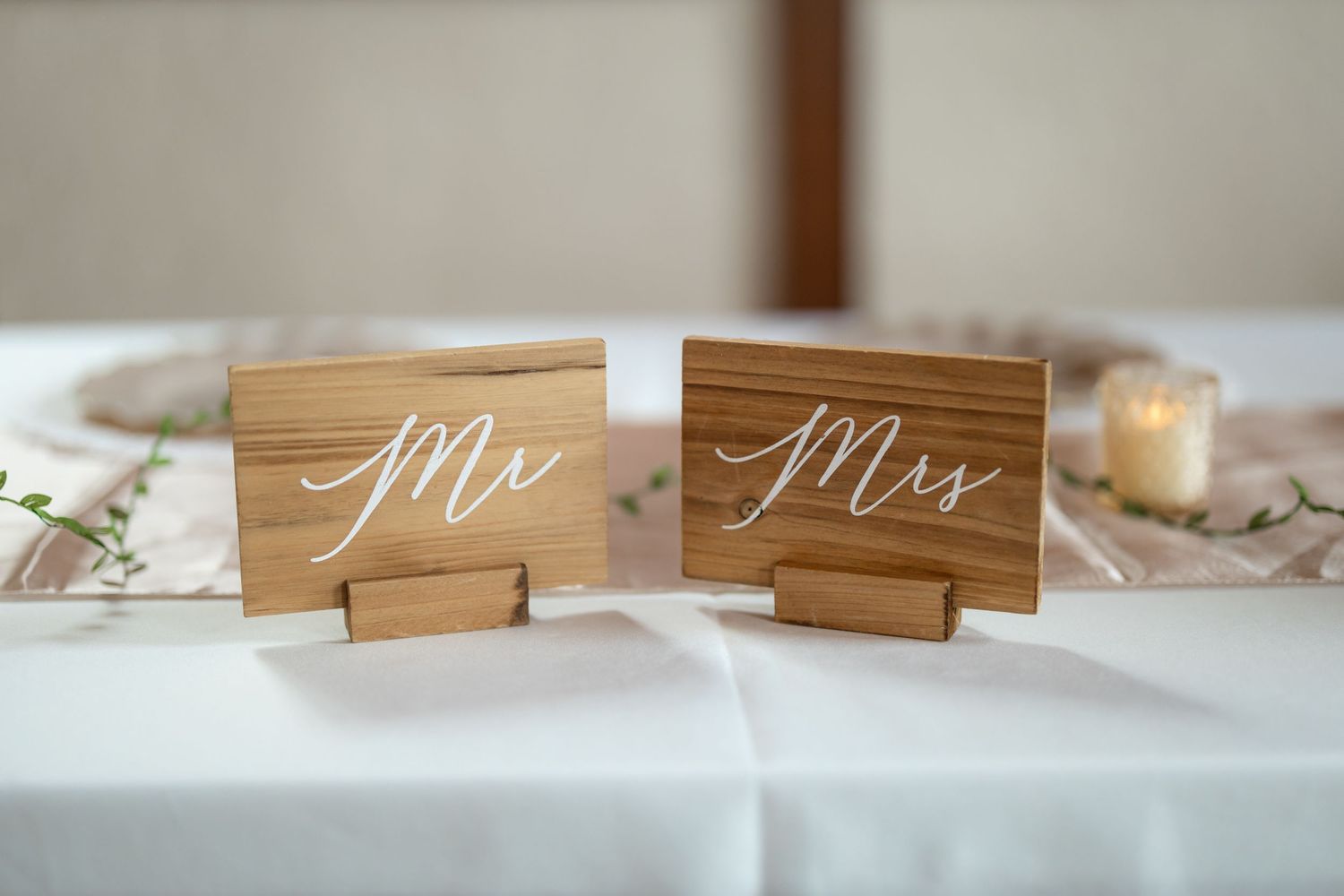 Wooden Mr and Mrs signs displayed on white tablecloth at wedding reception.