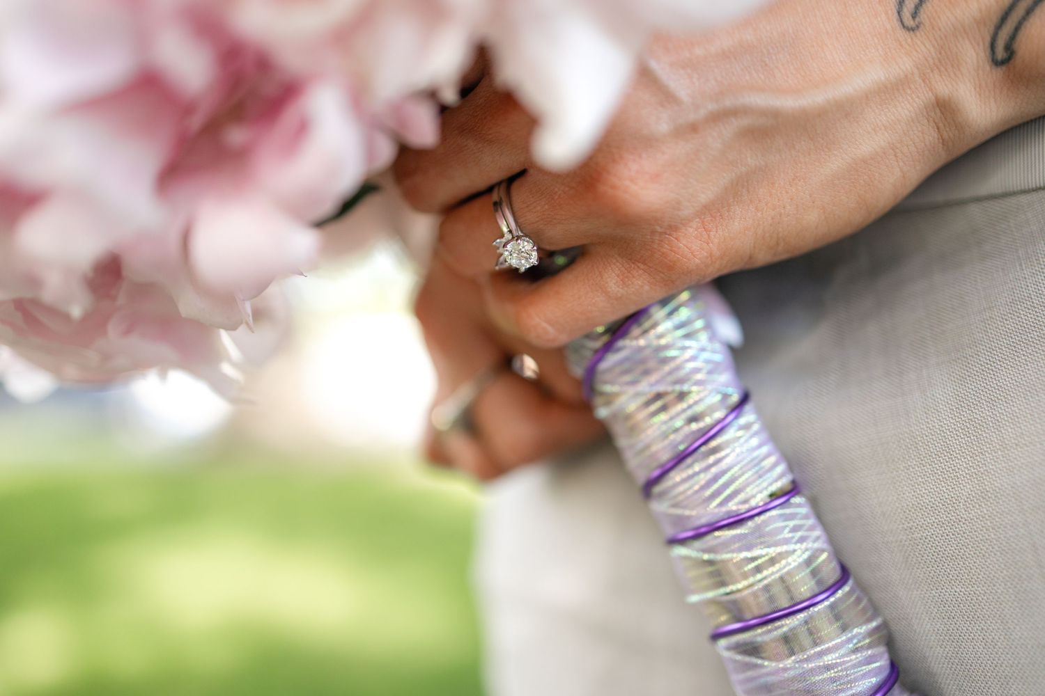 Detail shot of wedding rings with soft pink flowers in the background.