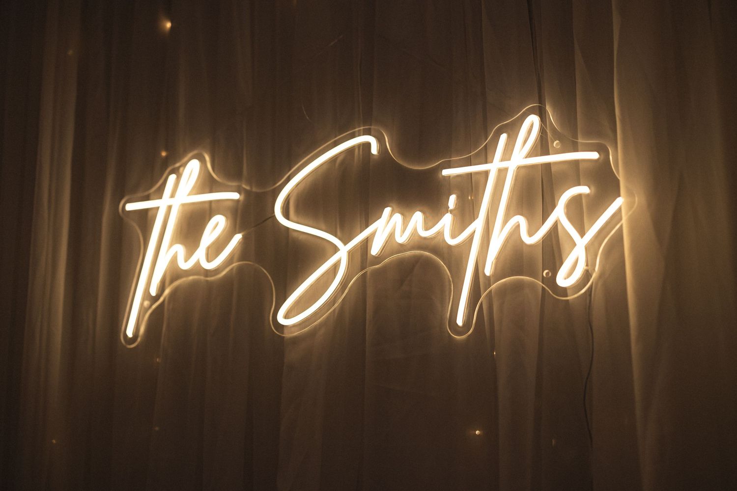 Illuminated cursive neon sign reading 'The Smiths' against a dark backdrop.