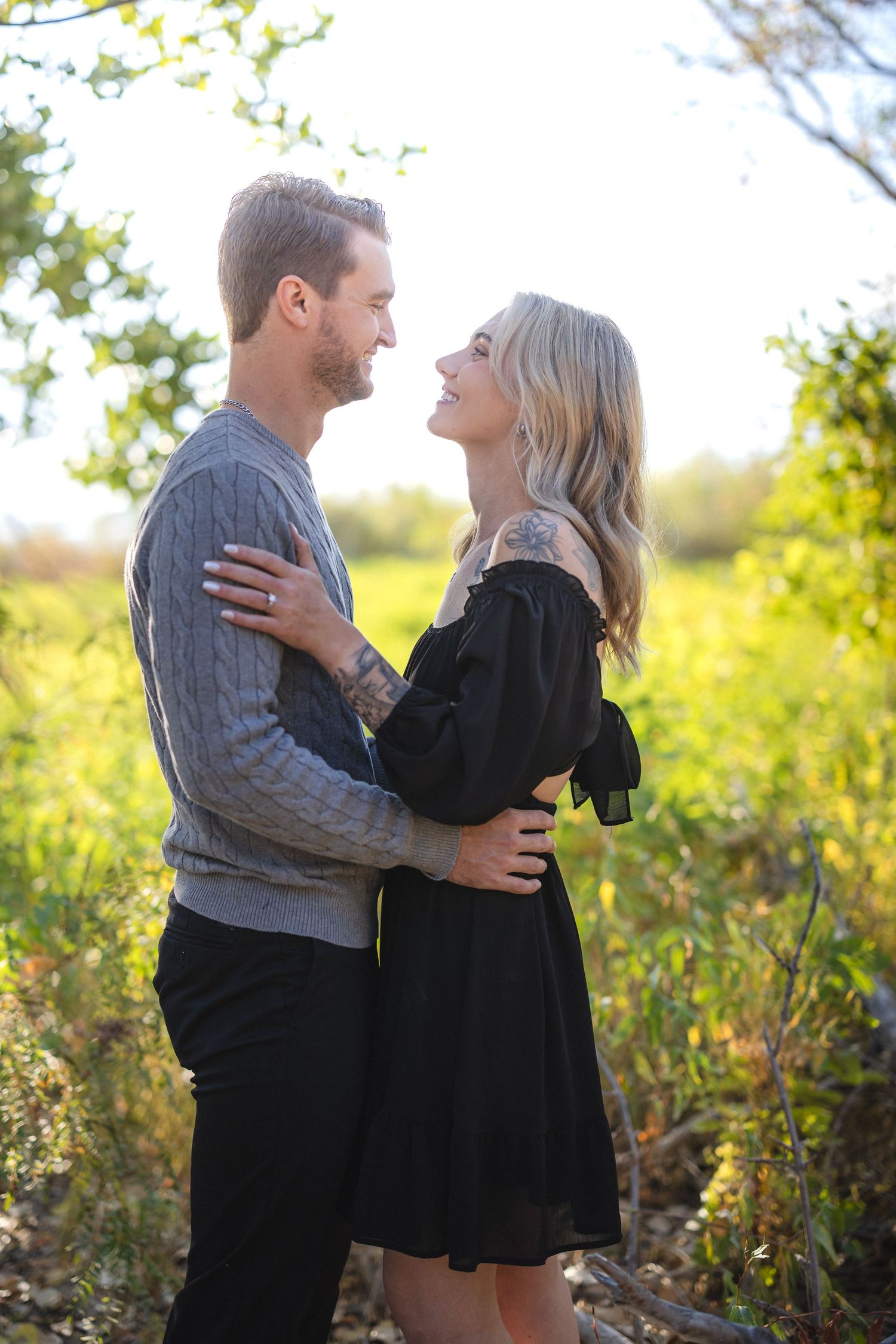 Happy couple laughing together during outdoor portrait session in natural setting.