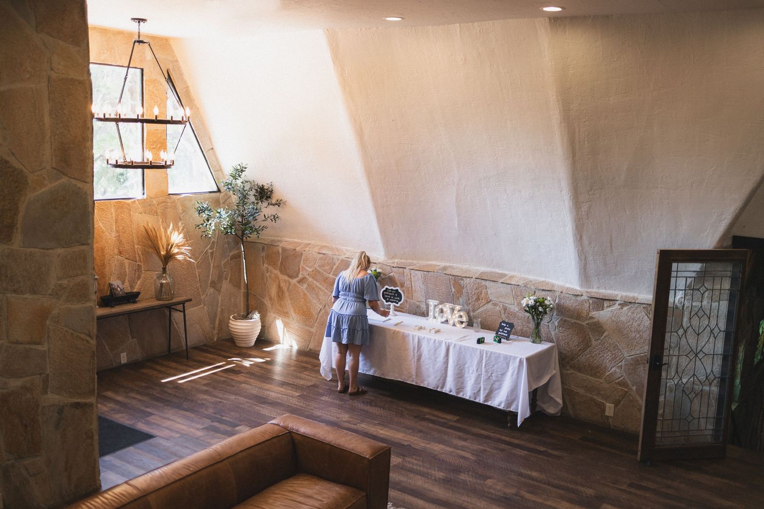An elegant reception room with stone walls and wooden floors featuring a decorated gift table.