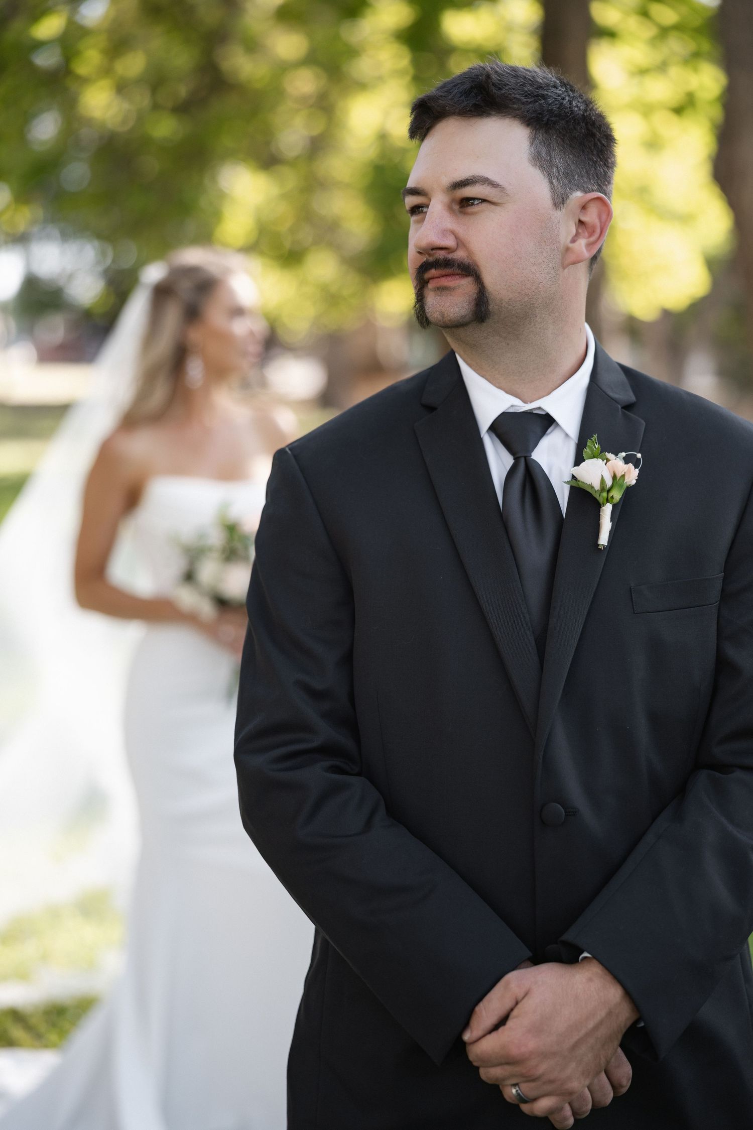 Wedding portrait with groom in black suit and boutonniere.