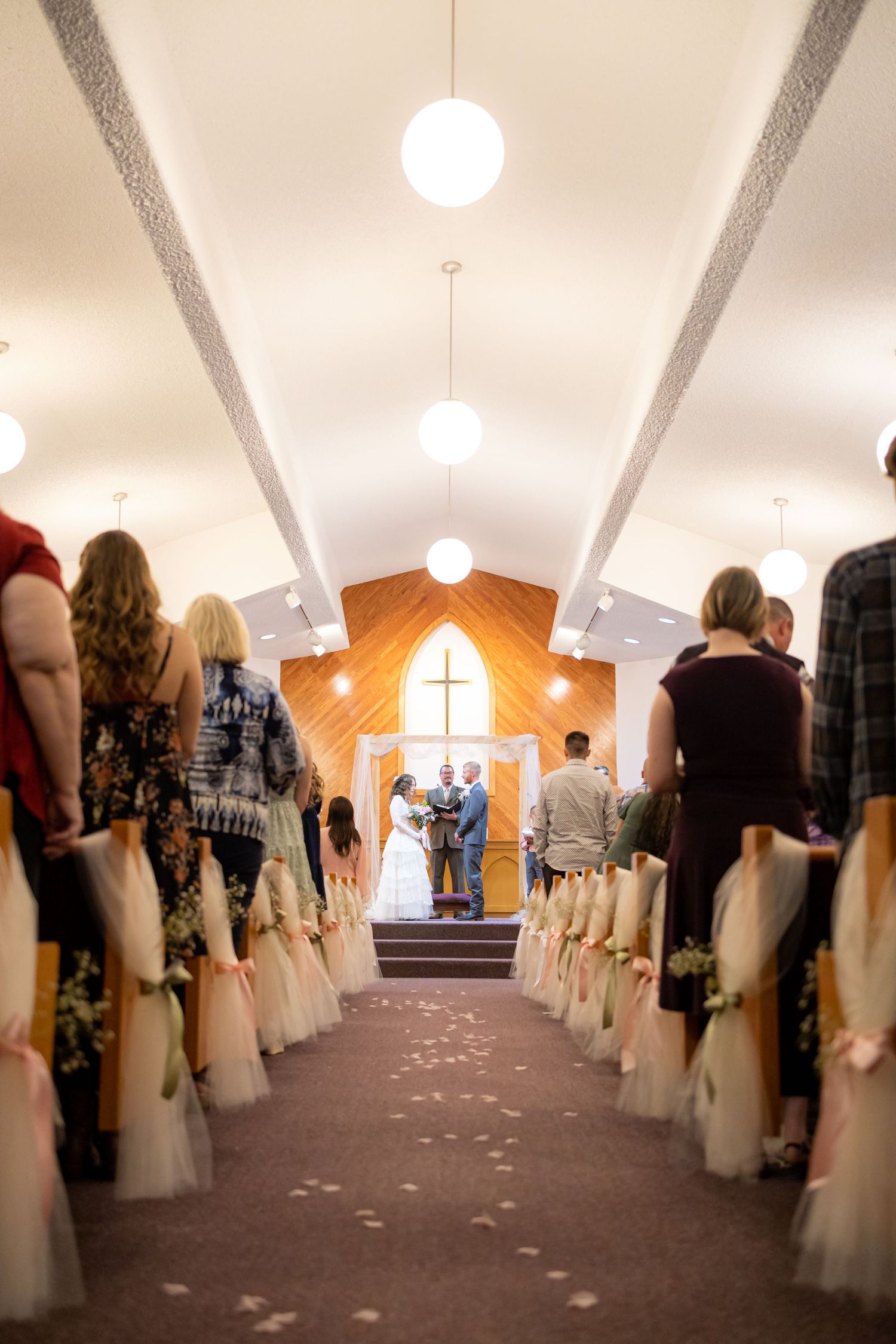 Wedding ceremony aisle decorated with white fabric and flower petals leading to altar.