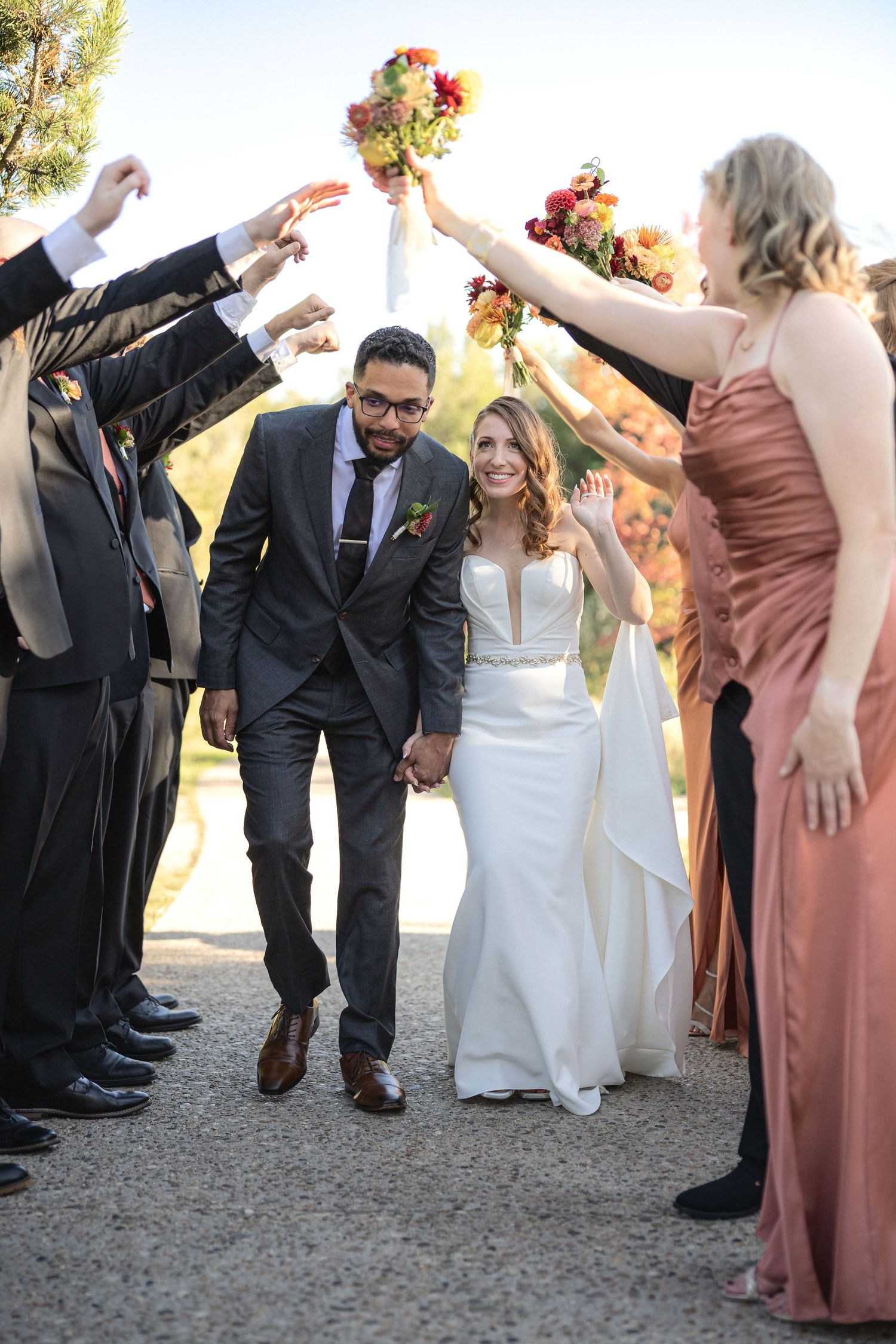 Wedding party performs fun group dance moves outdoors in formal attire.