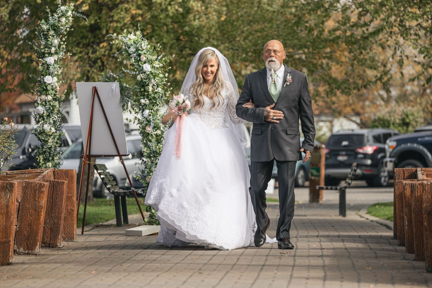 Wedding procession along a brick pathway with flowing white dress and formal attire.