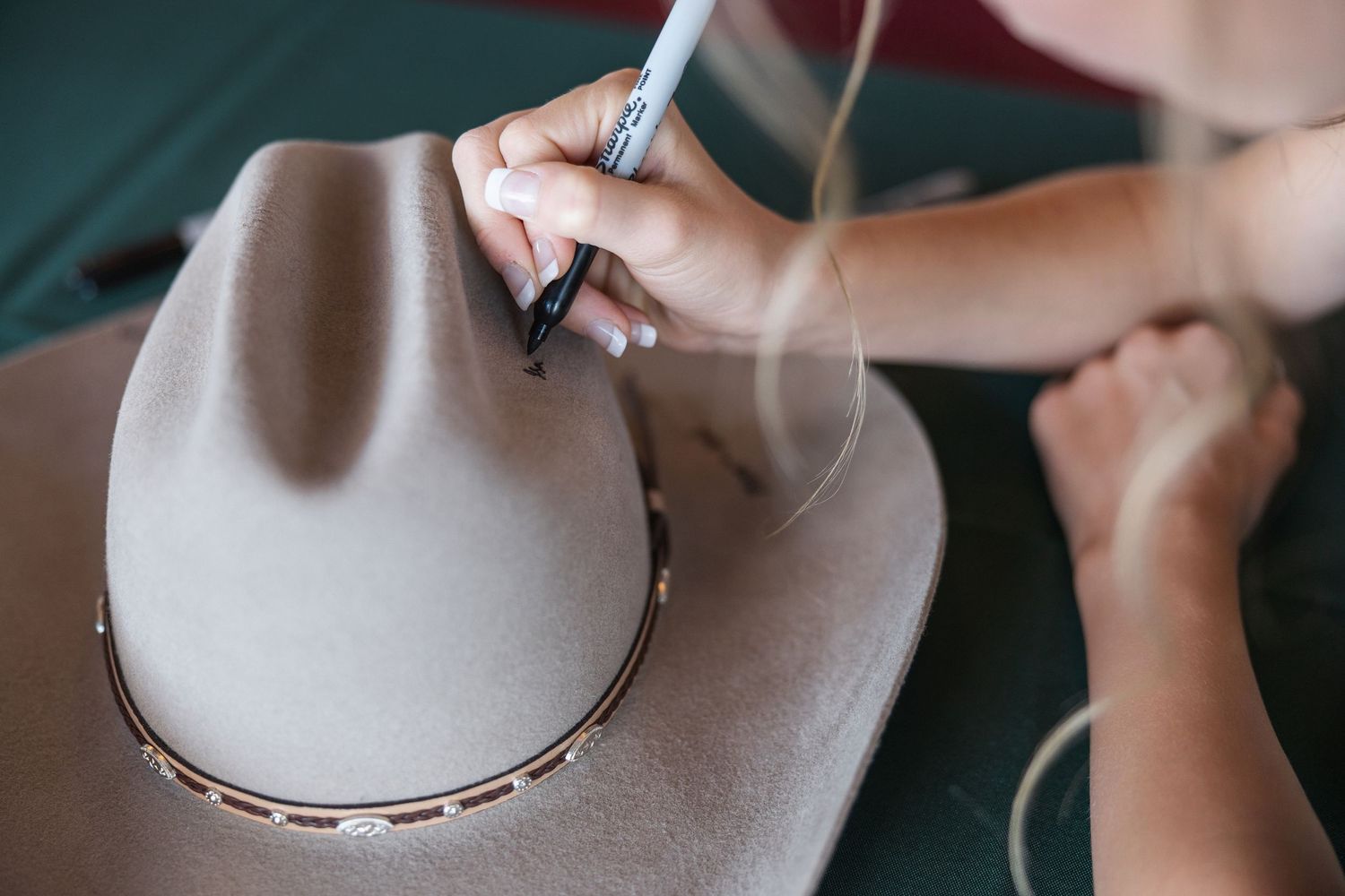 Close-up shots of hands adjusting a light gray felt hat.