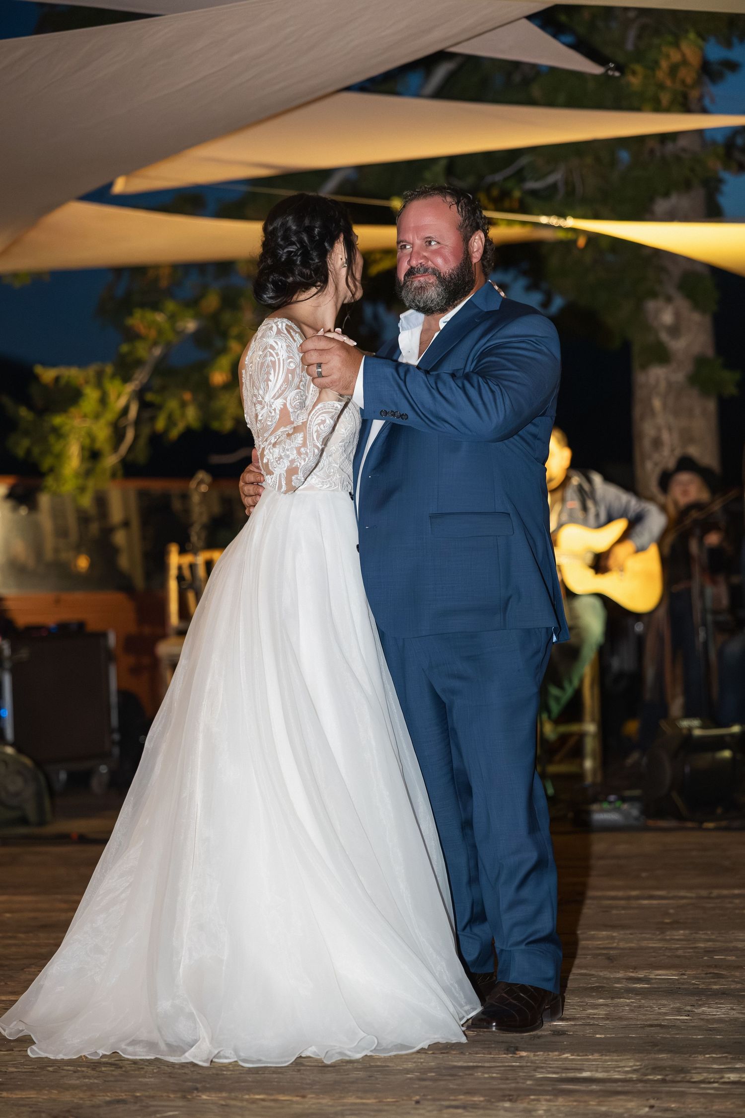 Couple sharing their first dance under outdoor canopy at evening wedding reception.