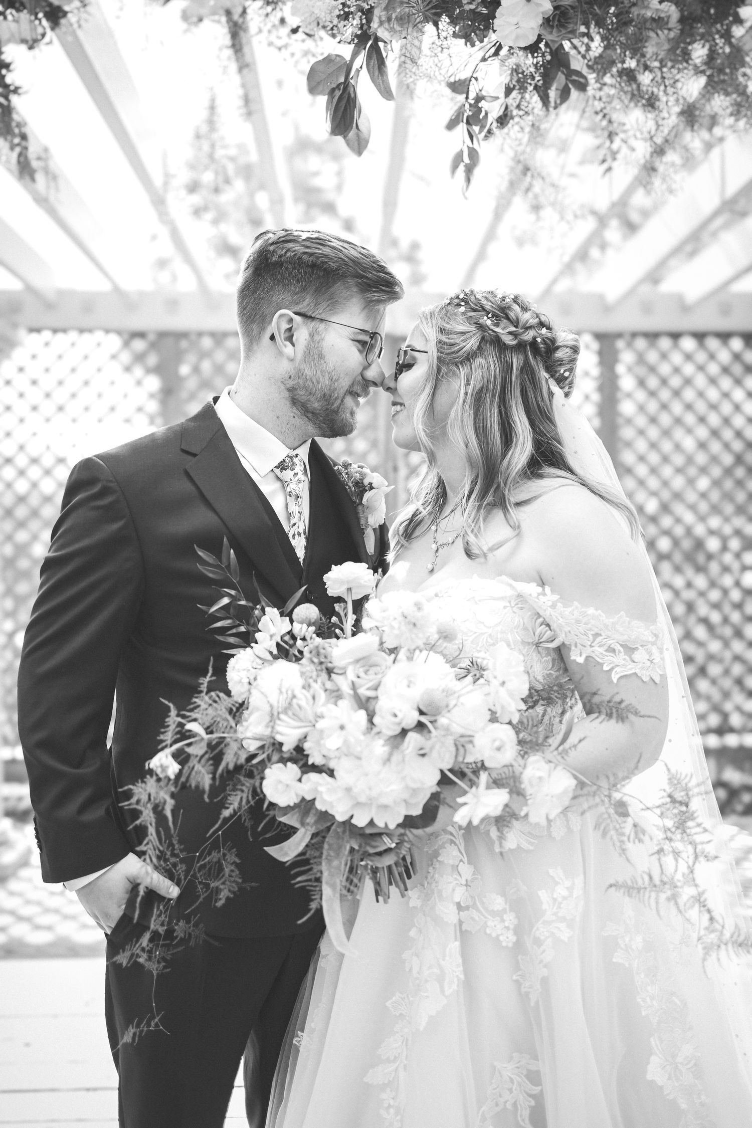 Wedding couple sharing intimate moment with bridal bouquet in garden setting.