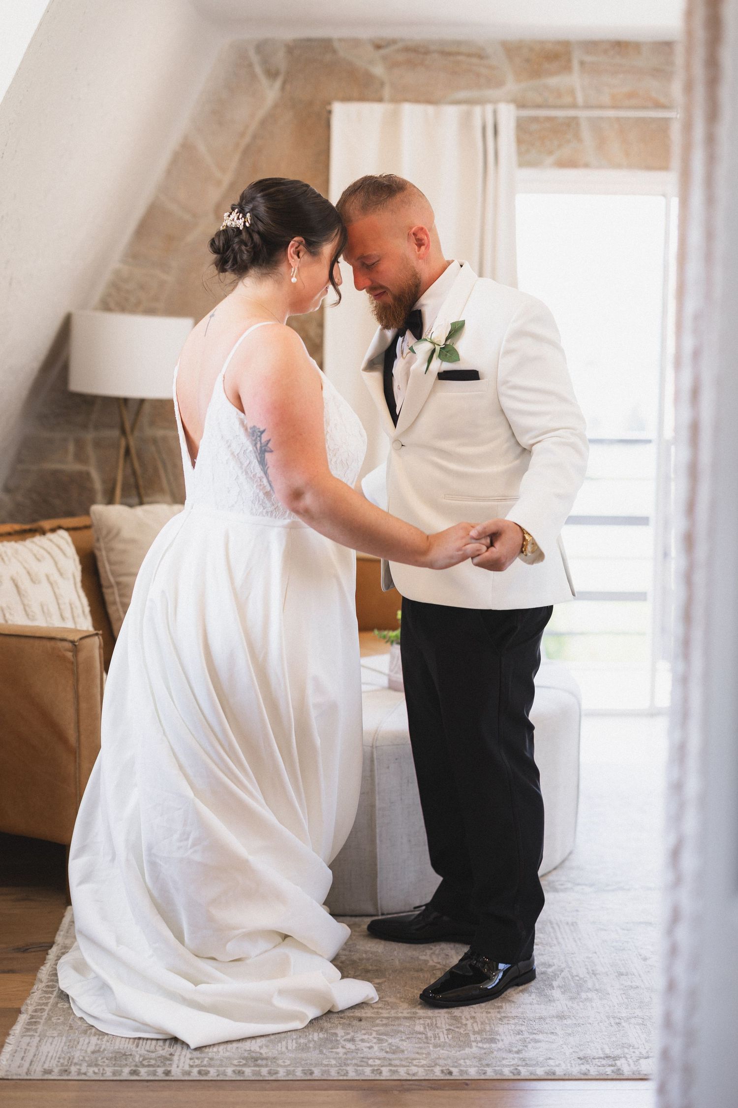 A tender moment shared between a couple during their first look in an indoor setting.