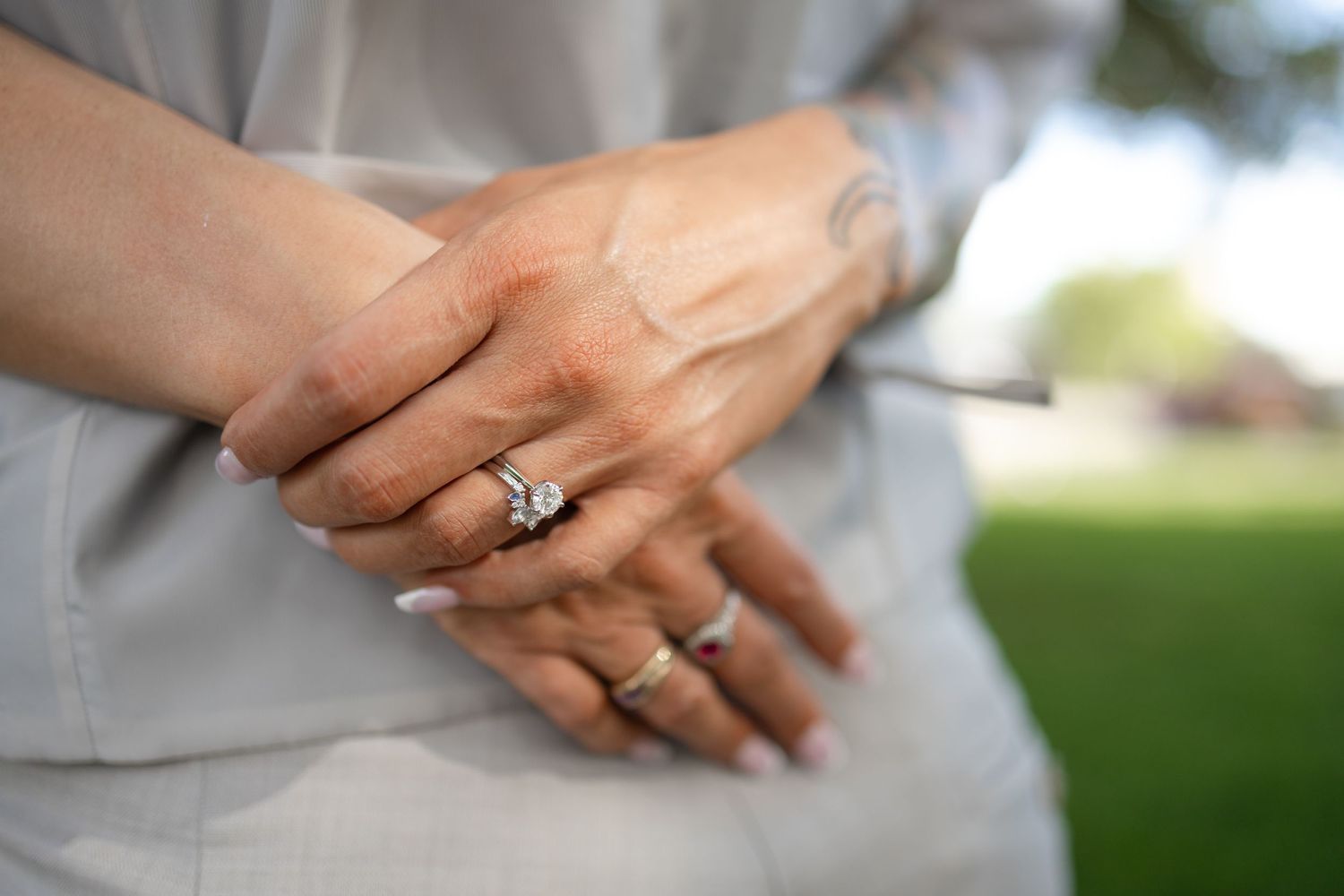 Close-up of hands showing wedding rings against light gray attire.