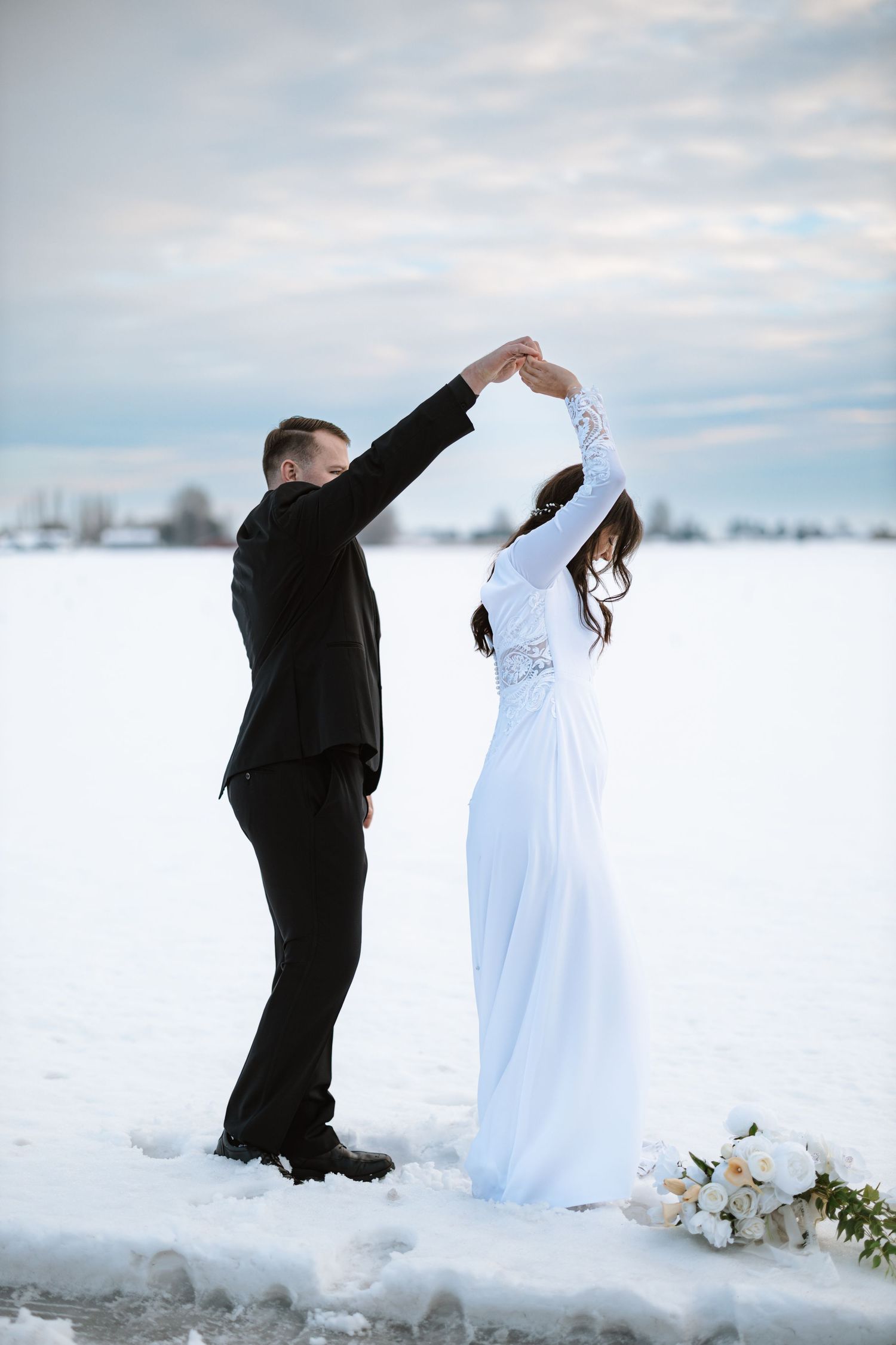 A couple shares a dance in contrasting black and white formal wear on a snowy winter day.