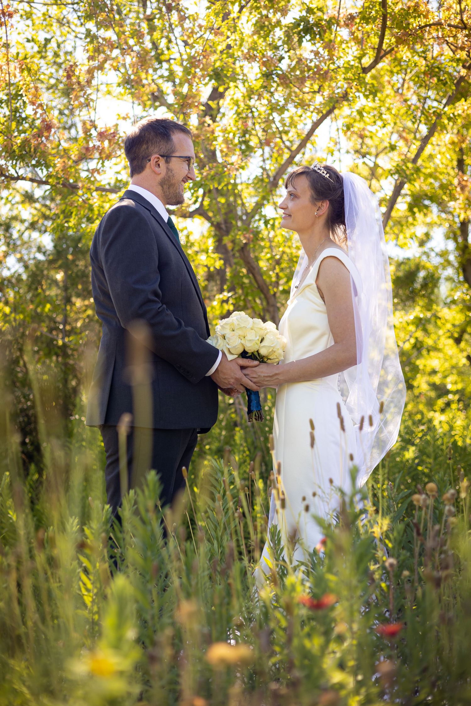 Wedding couple embracing in a field of wildflowers during golden hour.