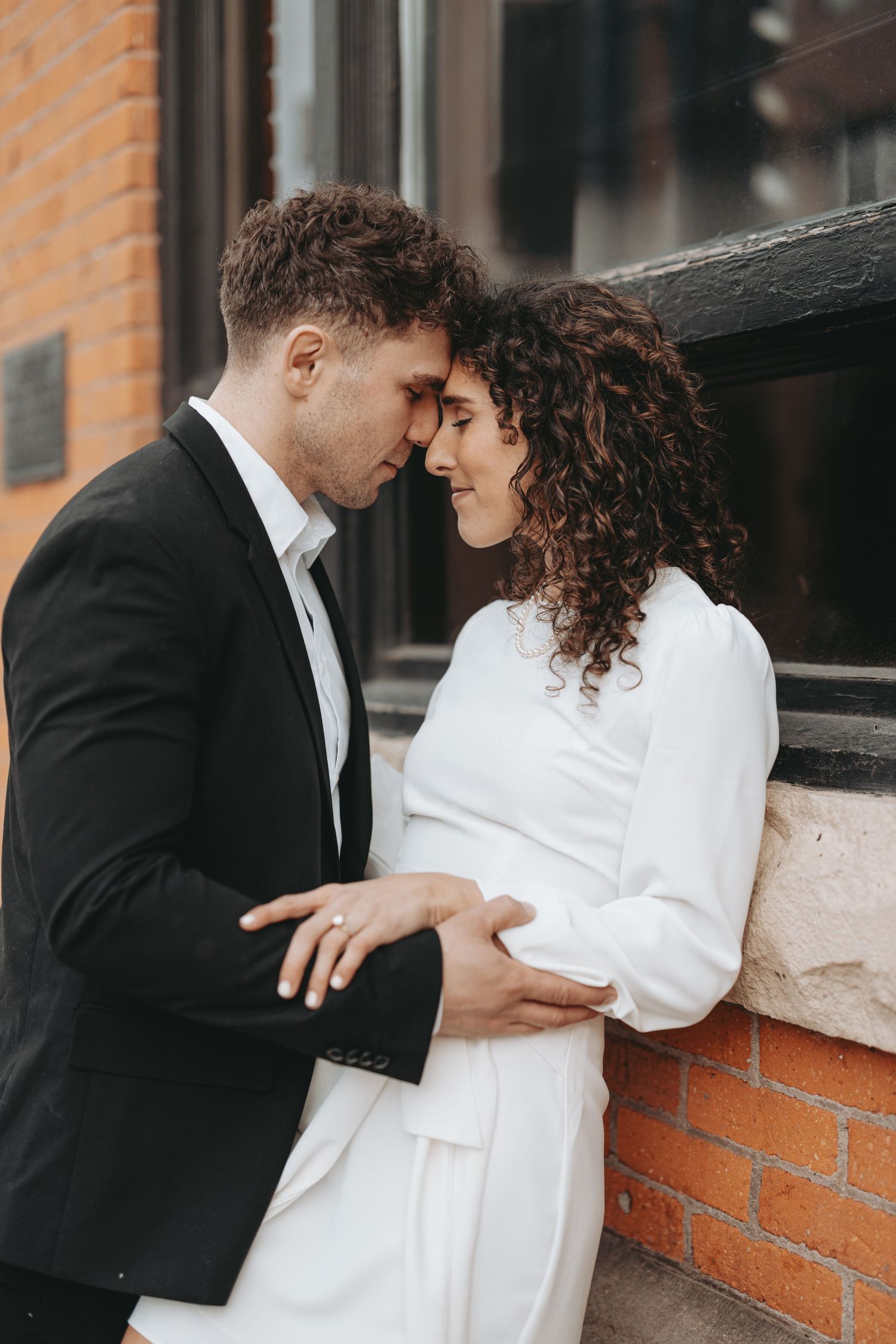 A tender embrace captured between a couple in black and white formal wear.