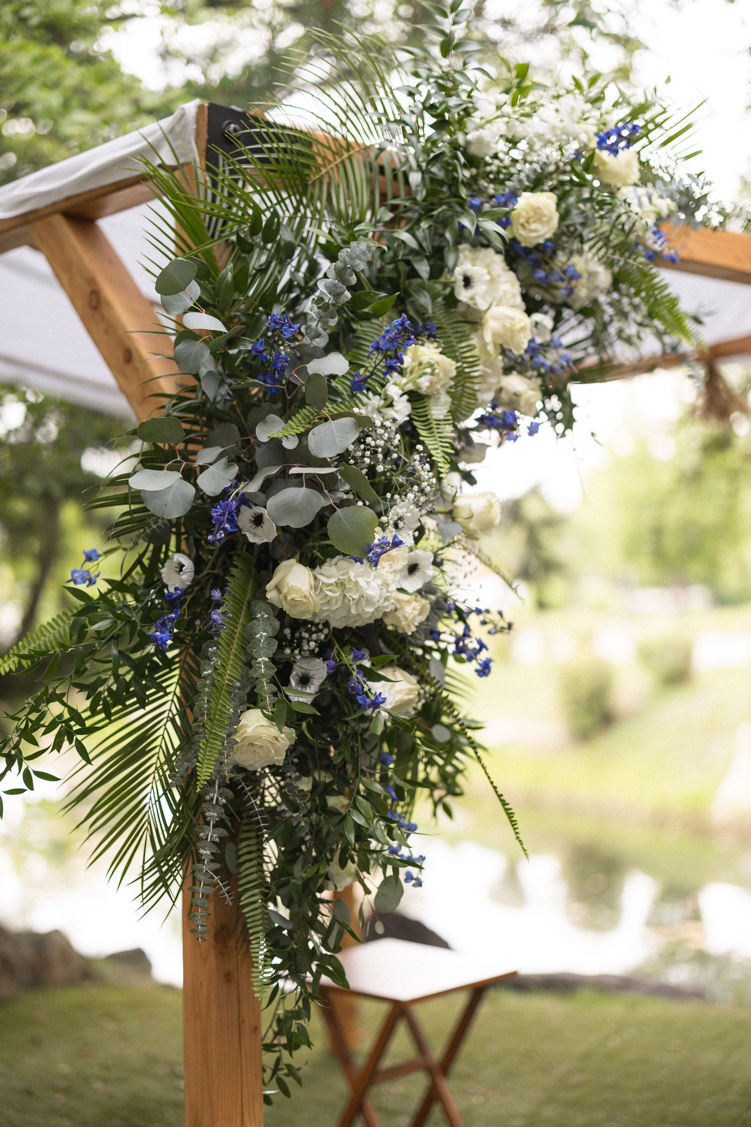 Lush floral wedding arch arrangement featuring blue and white flowers with greenery.