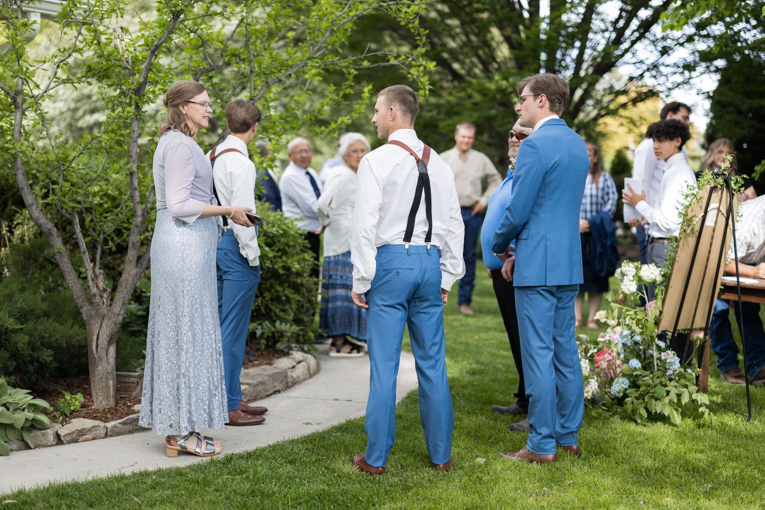 Wedding guests in casual attire mingling in garden setting.