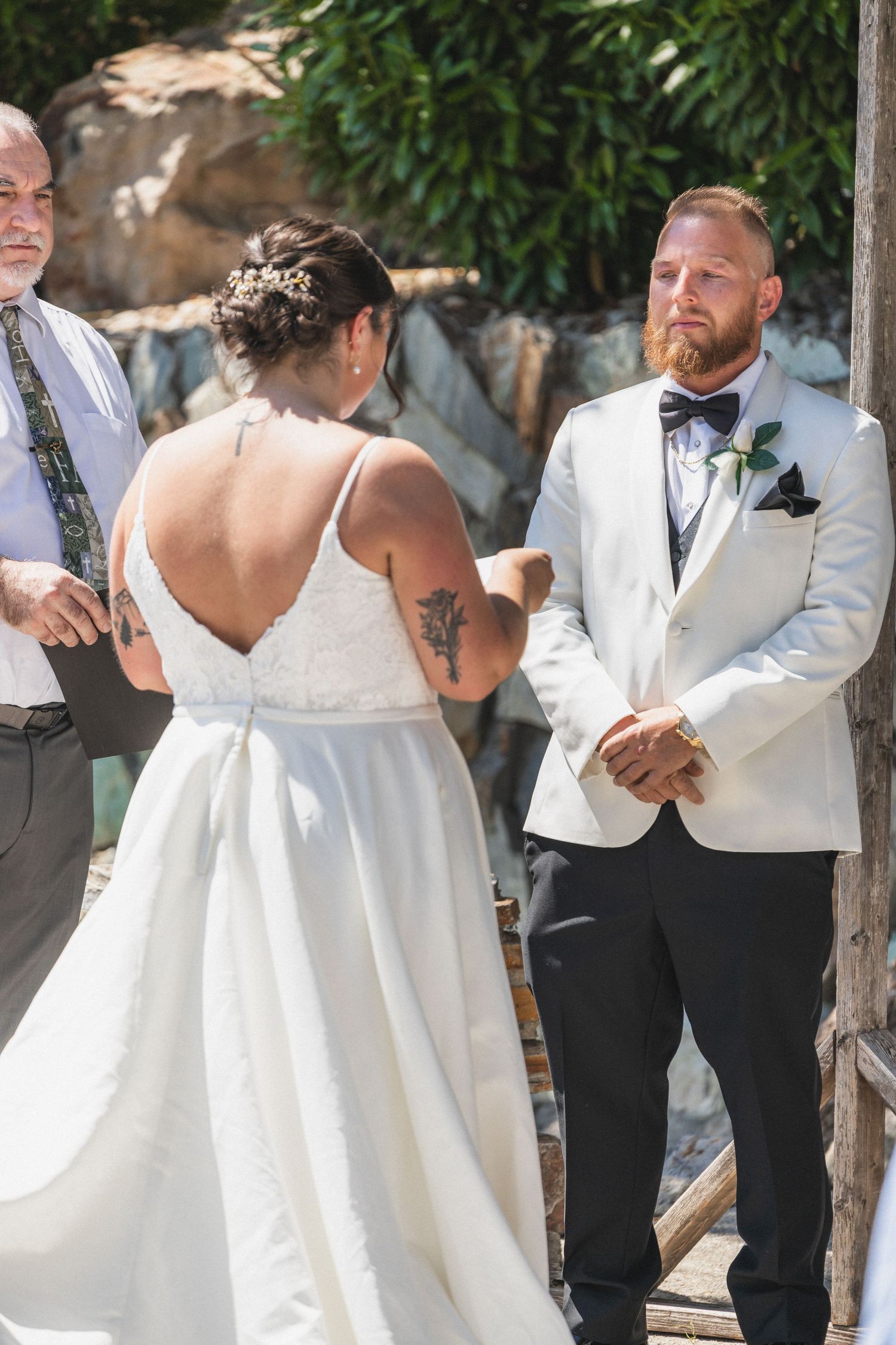 An outdoor wedding ceremony with a white-dressed bride and groom in formal attire.