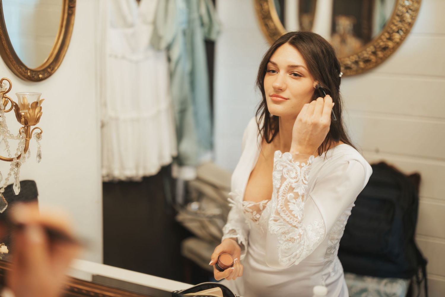 Getting ready moment in bridal suite with lace details.