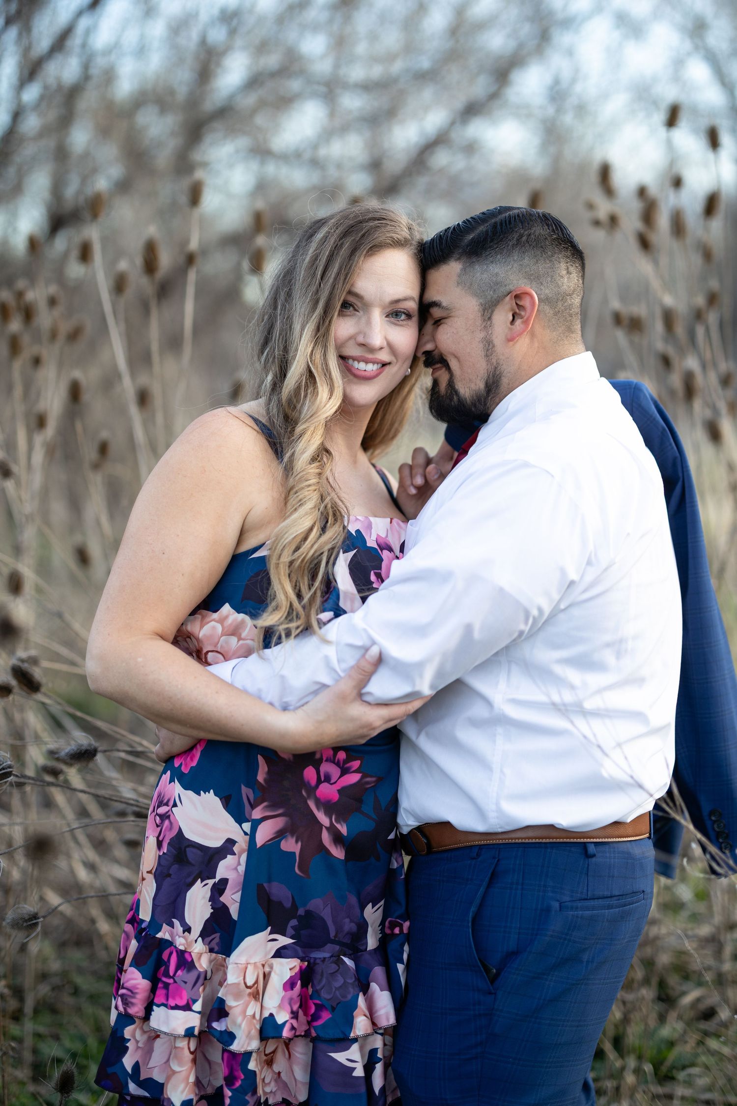 Romantic portrait of a couple sharing an intimate moment outdoors among dried plants.