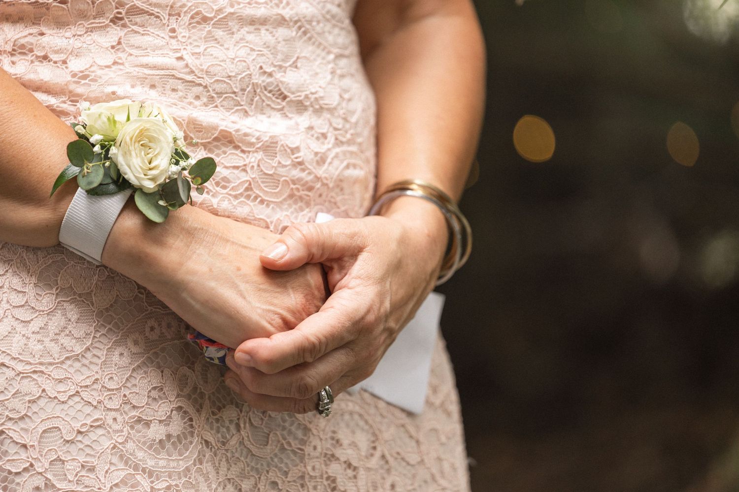 Close-up of a delicate white rose wrist corsage with silver ribbon.