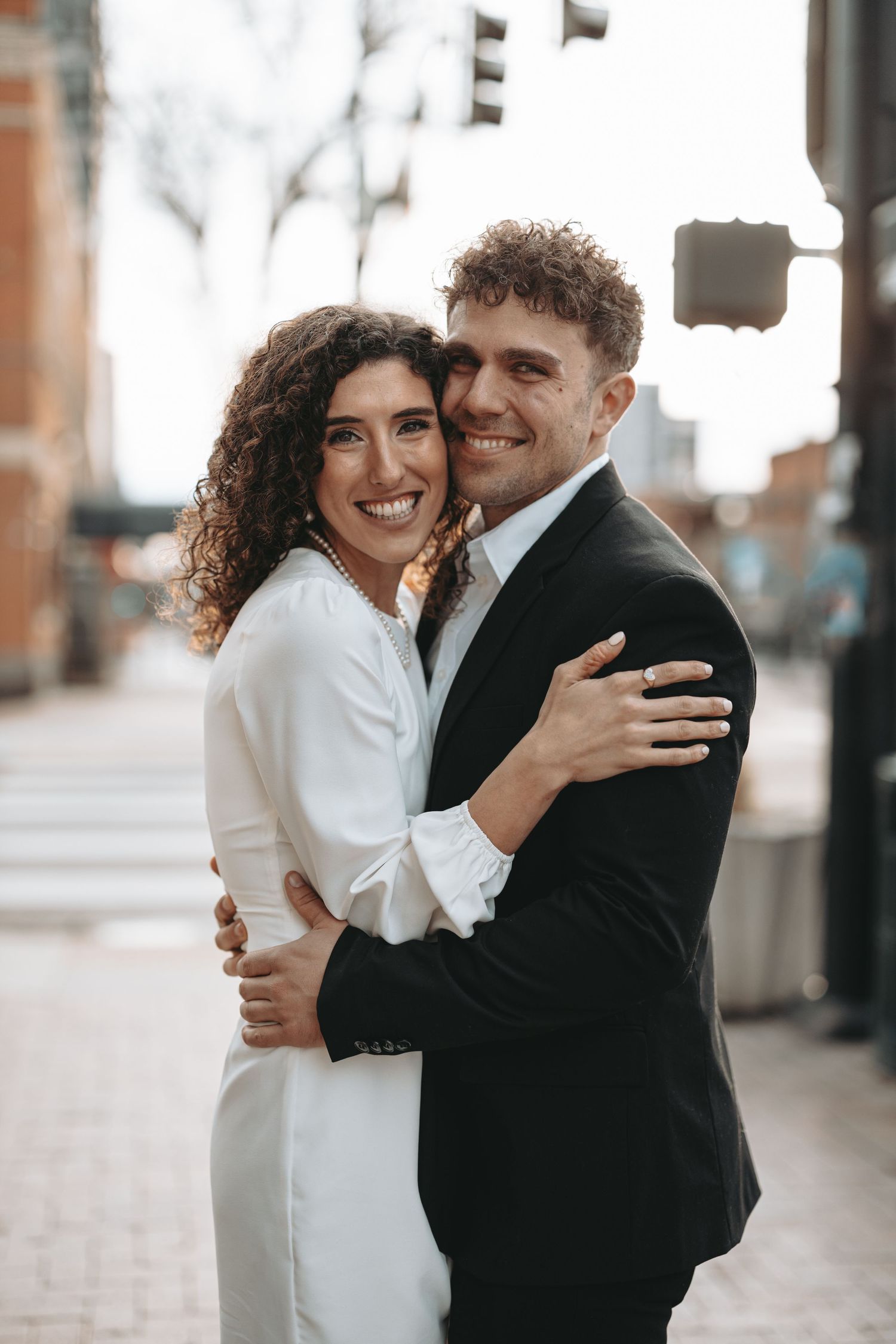 A happy couple in formal attire sharing a close embrace and smiling at camera.