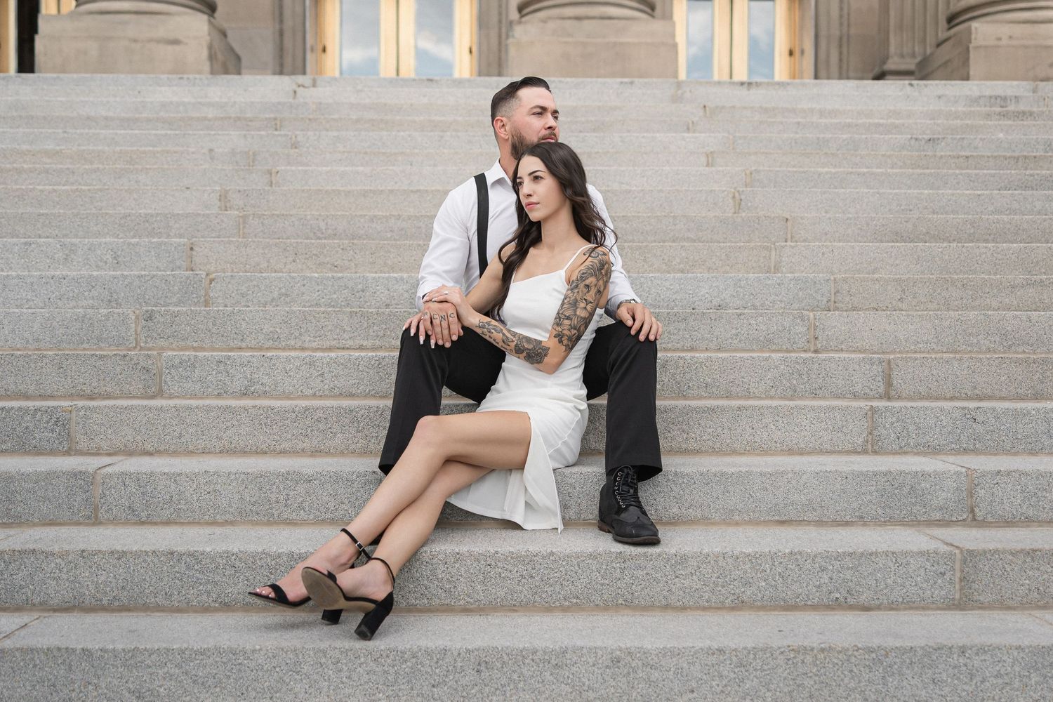Couple sitting on grand stone steps of classic building exterior.