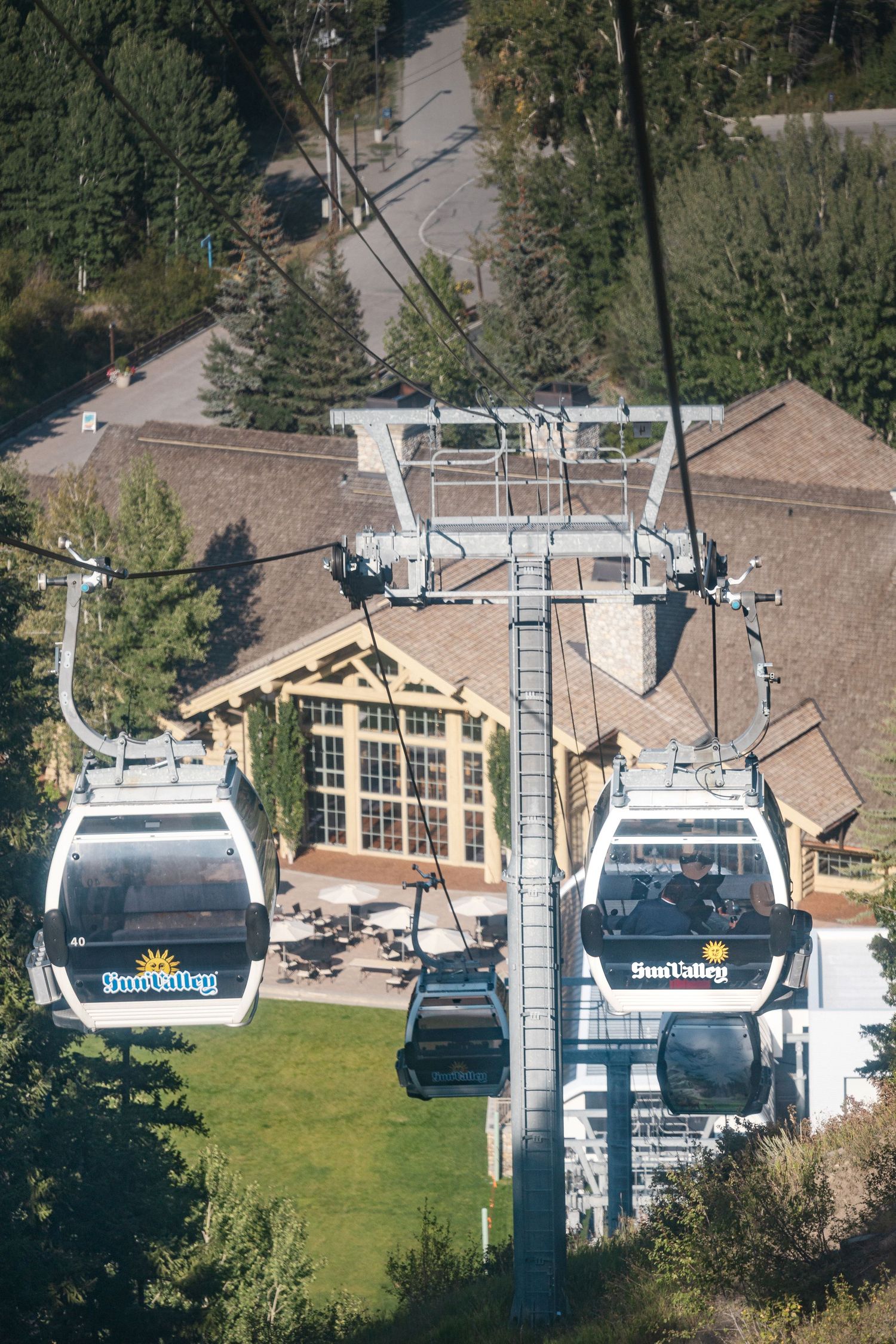 Ski resort gondola lift system with white cabins against mountain landscape.