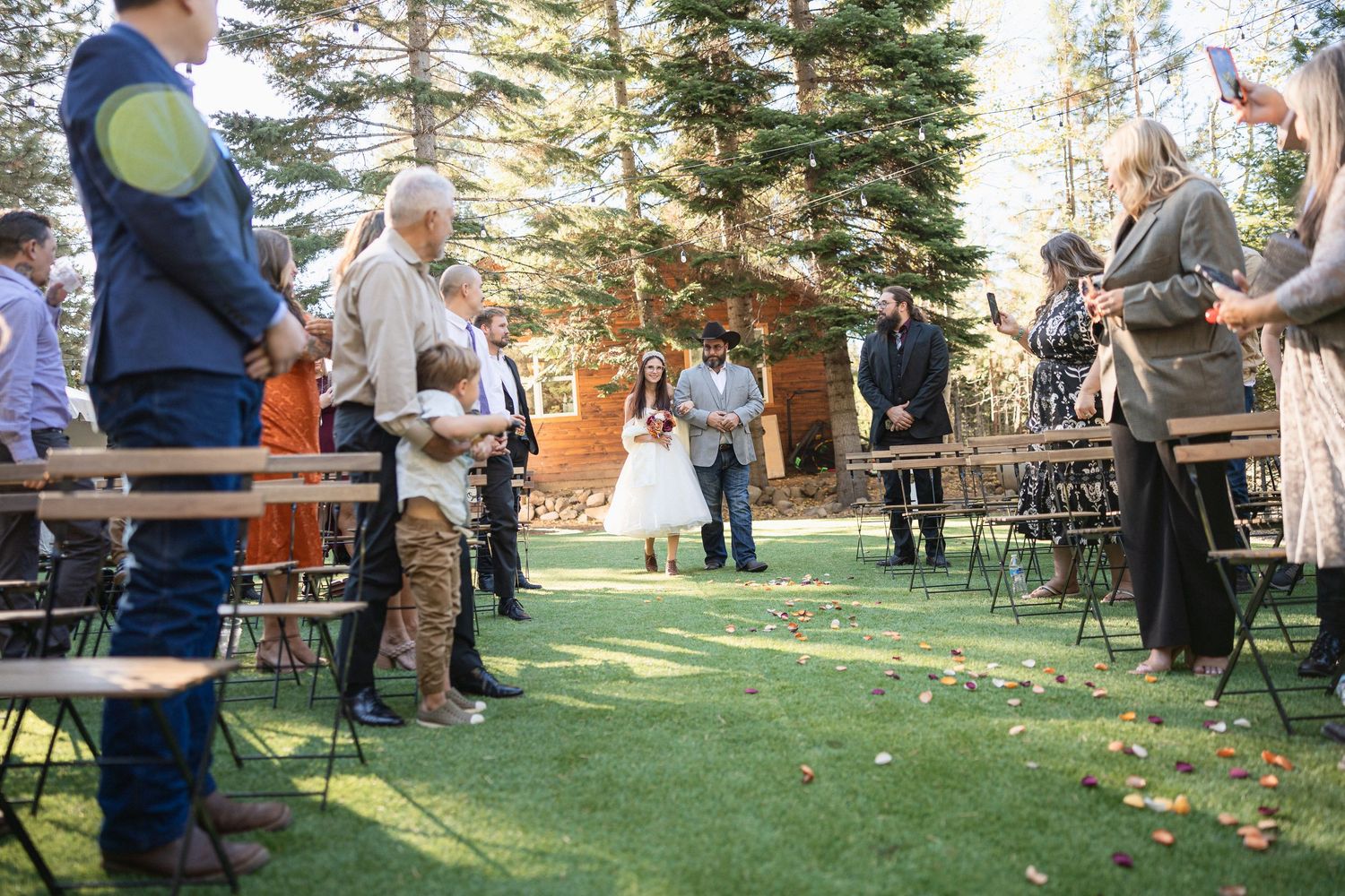 Wedding guests gathered on lawn with folding chairs during outdoor ceremony.