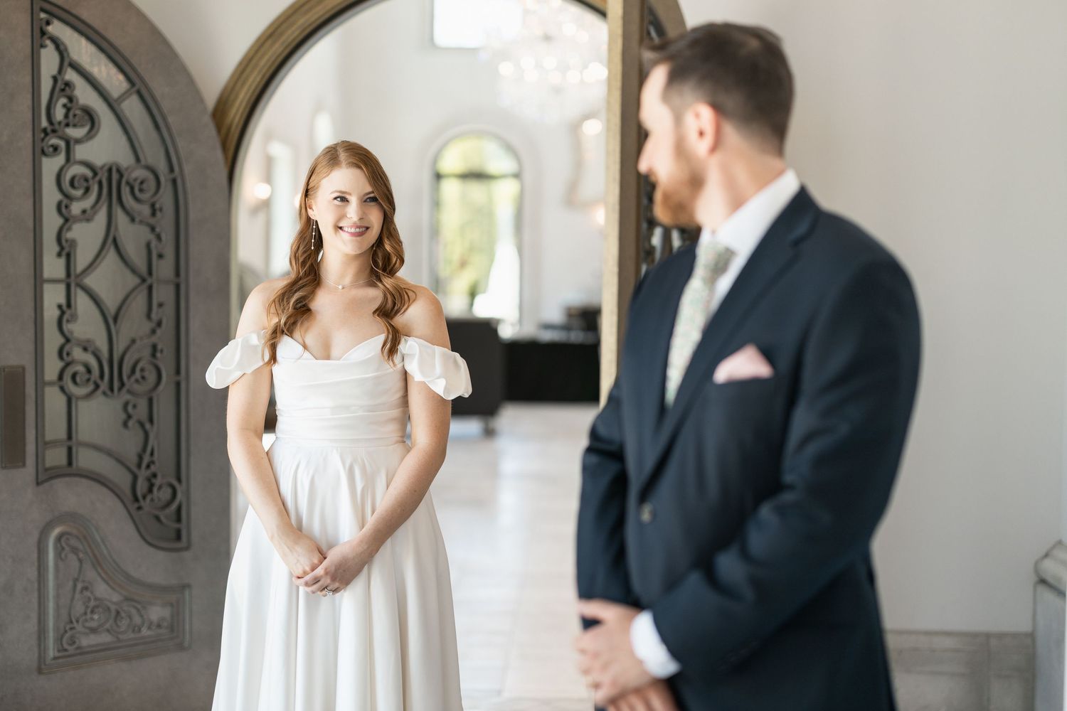 Couple exchanges glances during their first look in an elegant indoor setting.