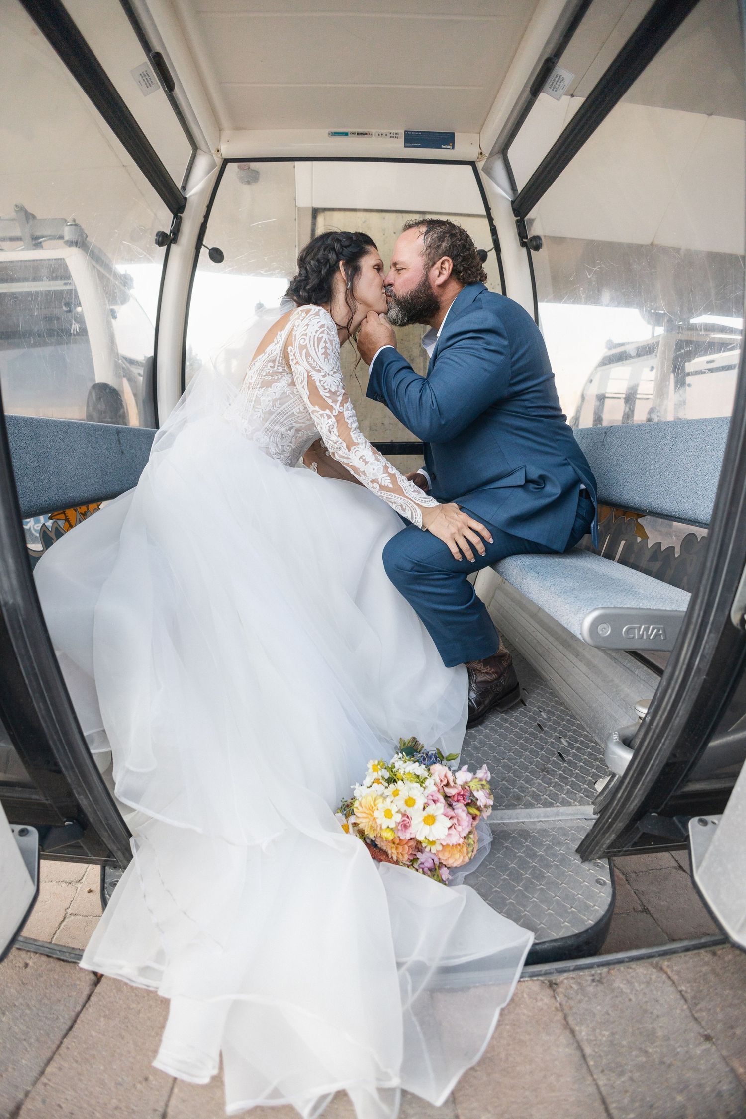 Couple in wedding attire sharing intimate moment inside white vehicle interior.