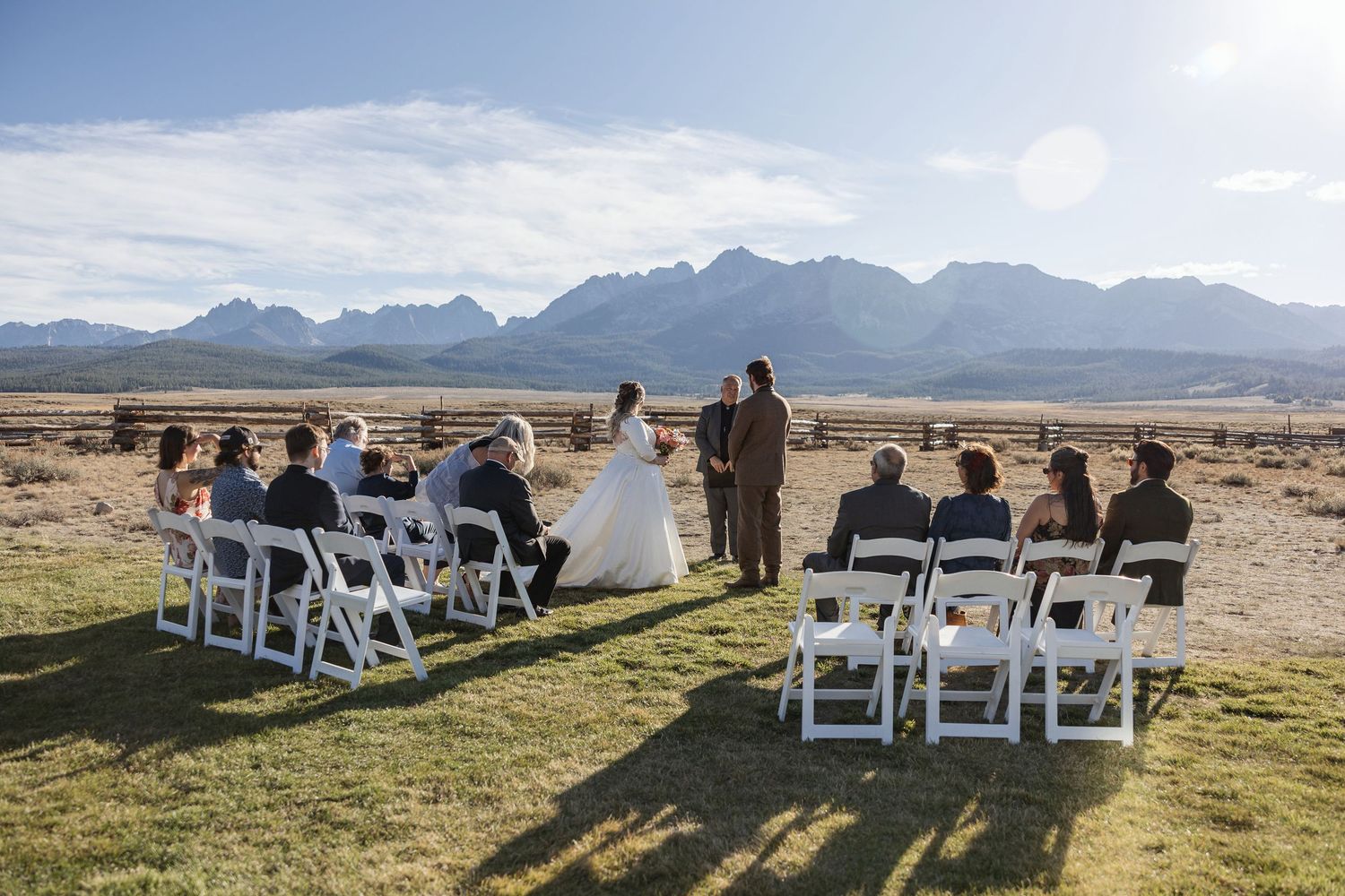 Wedding ceremony setup with white chairs arranged outdoors against mountain backdrop.