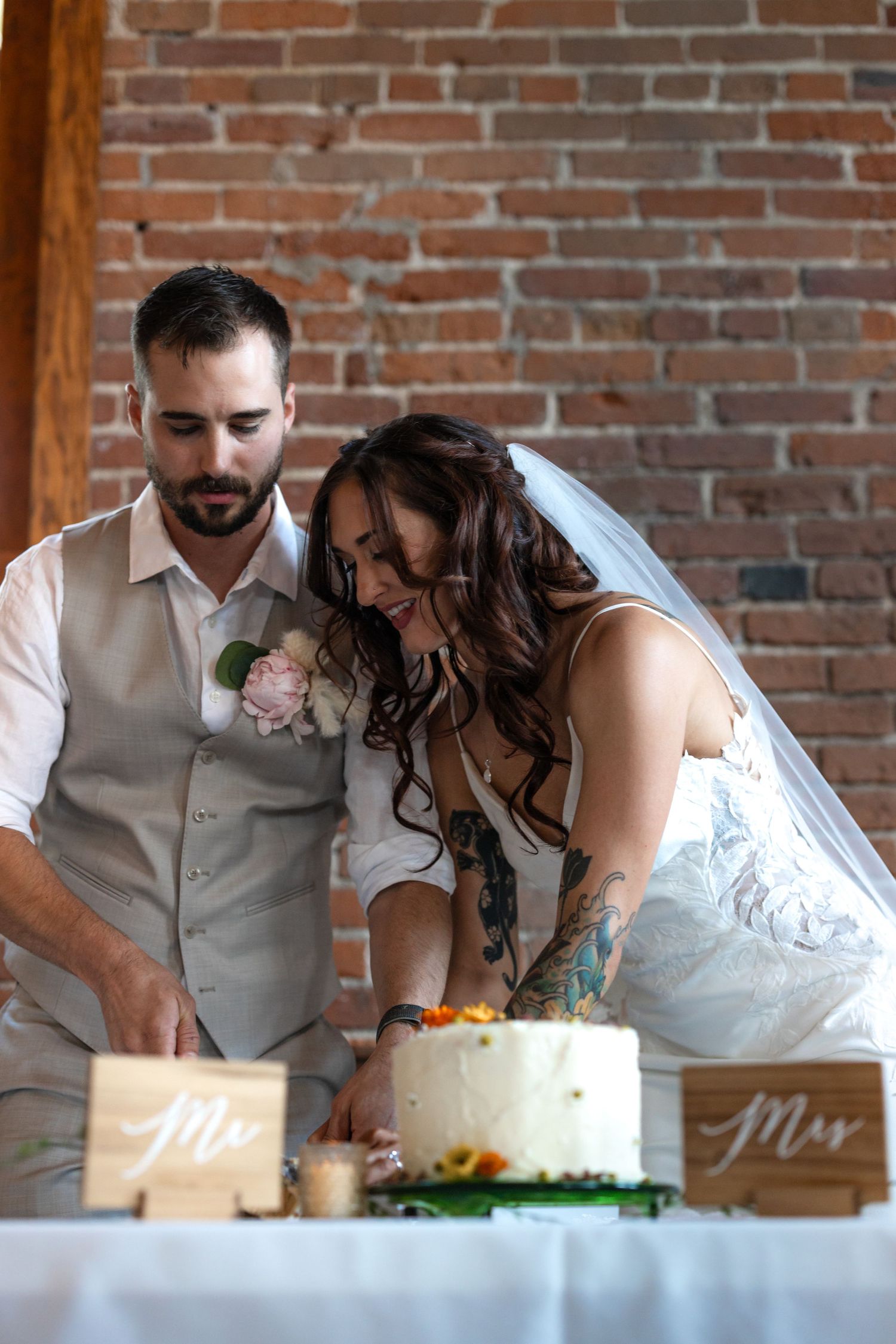 Couple shares intimate moment while cutting their wedding cake with Mr and Mrs signs.
