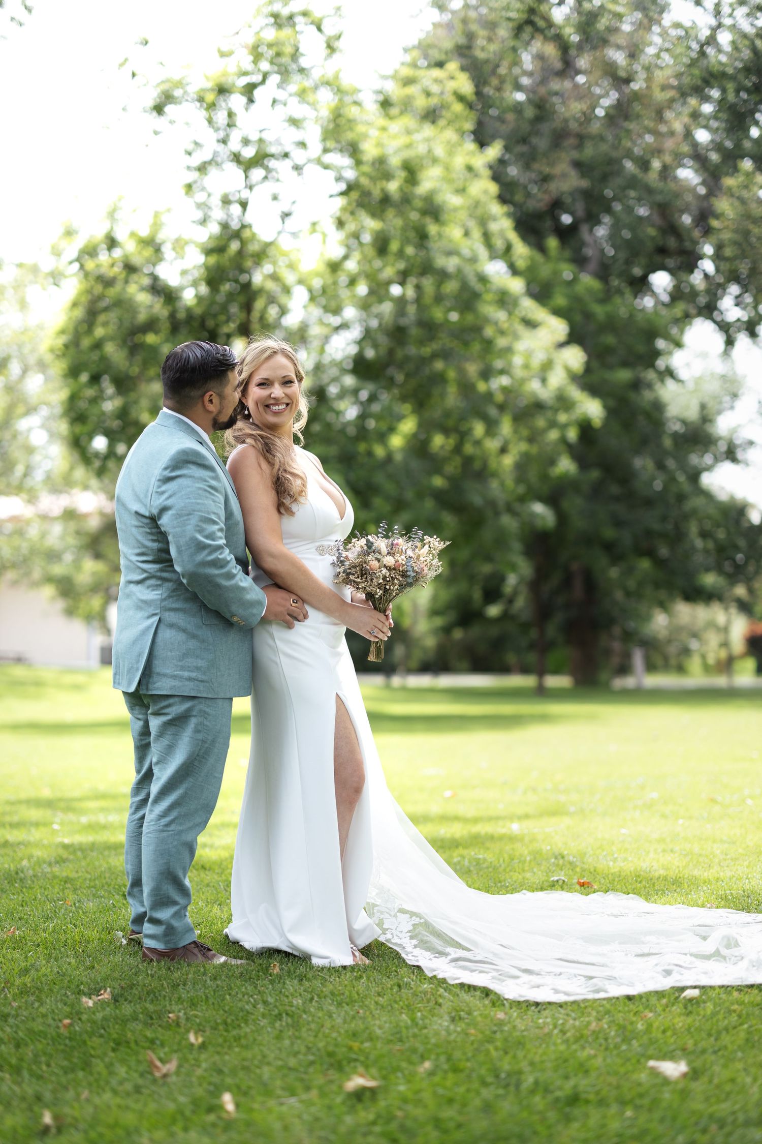 Newlywed couple poses for romantic portrait in garden setting.