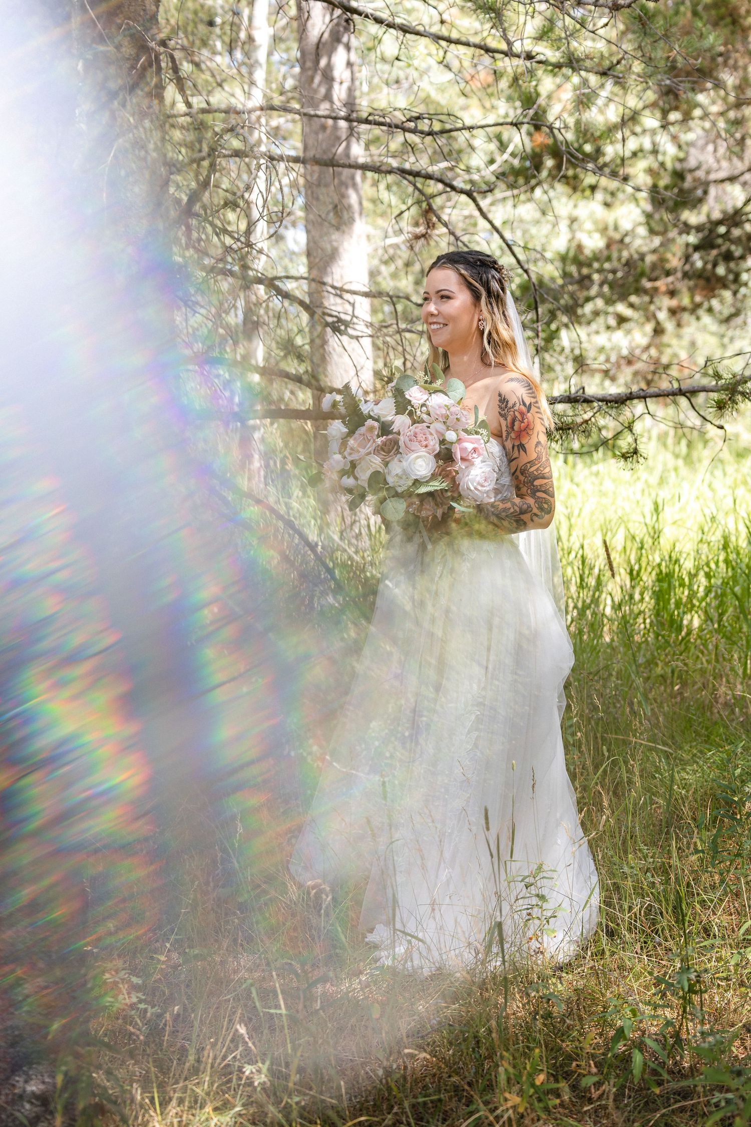 Sunlit portrait of person in white dress holding floral bouquet in forest setting.