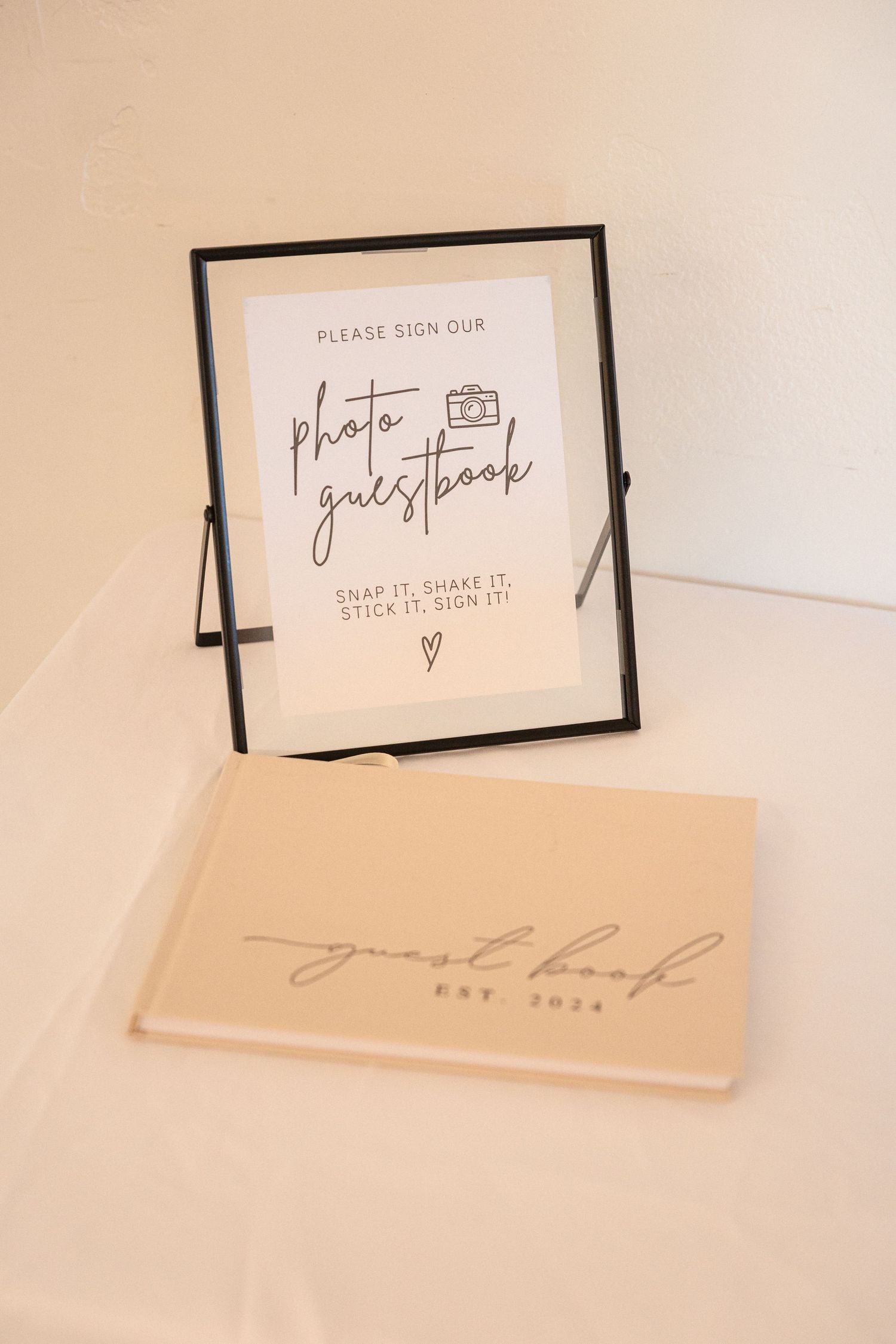 A framed photo guestbook sign with minimalist design on a white surface.