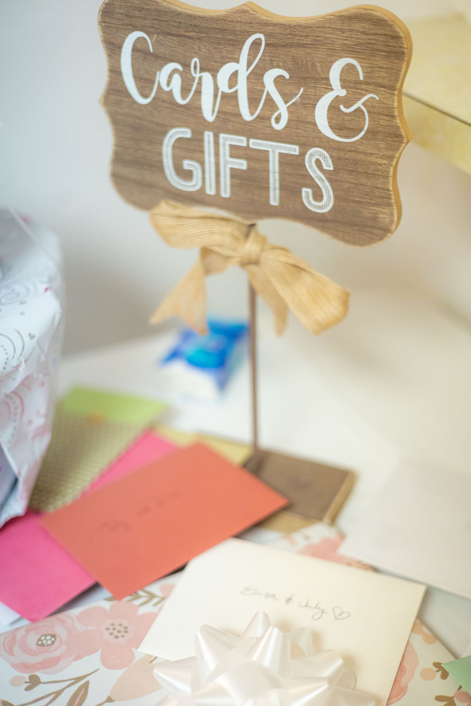 Rustic wooden sign reading 'Cards & Gifts' with decorative ribbon at wedding reception.