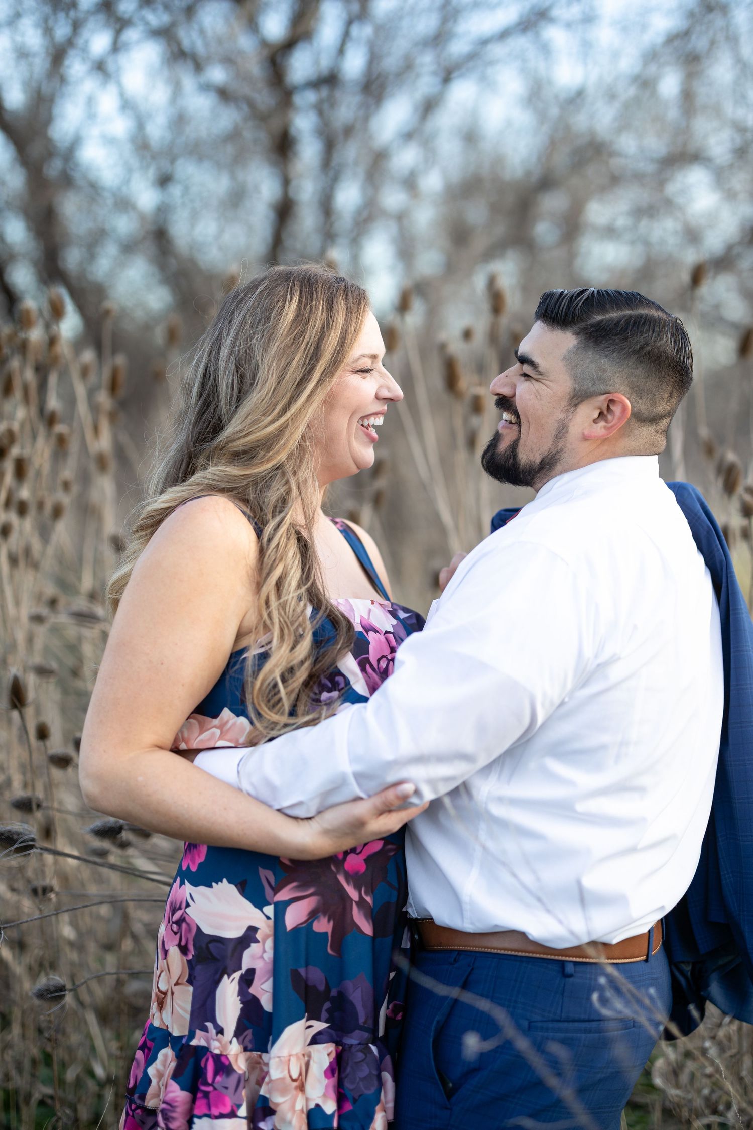 A couple shares a candid moment of laughter during their outdoor photoshoot.