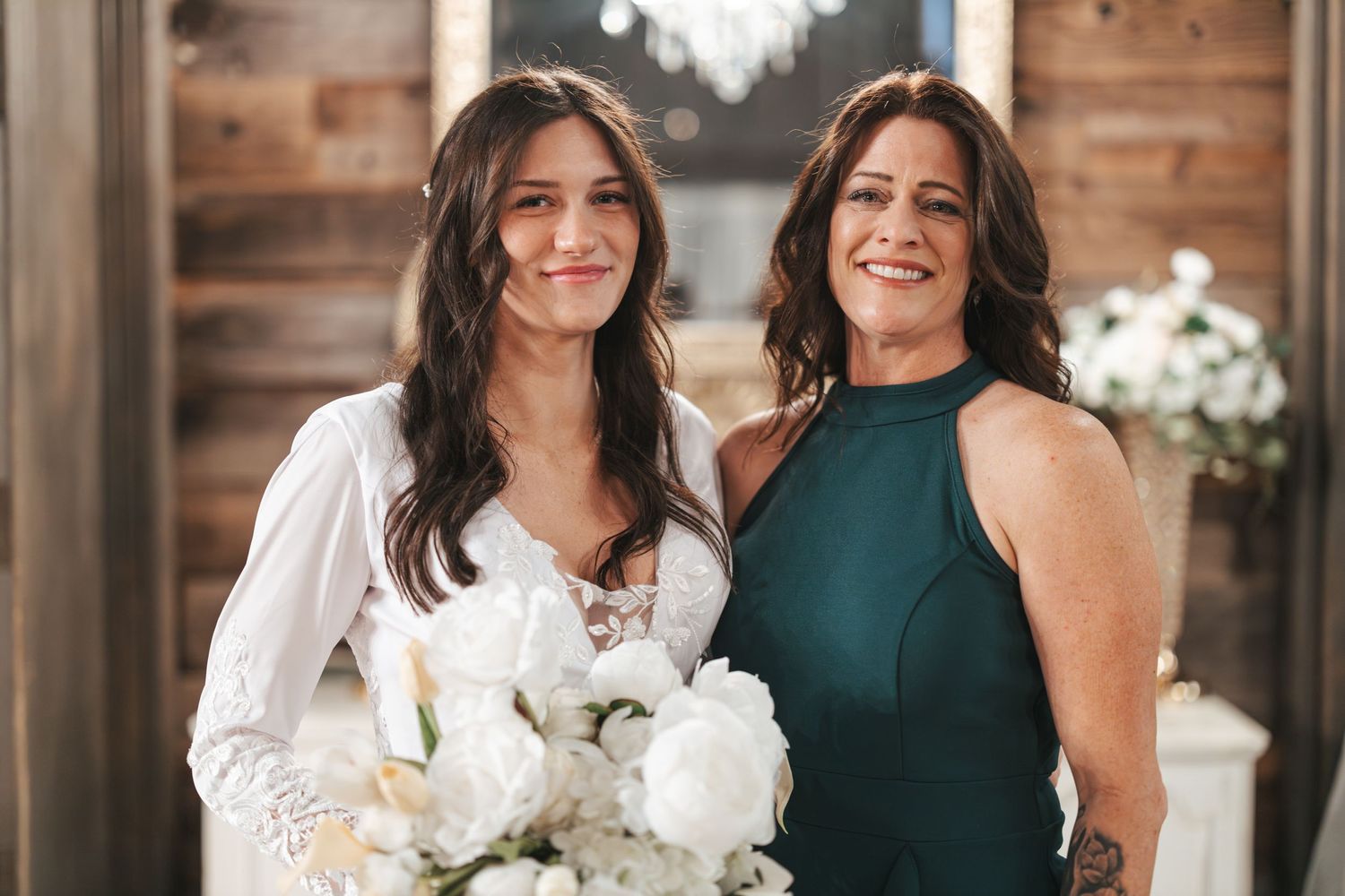 Wedding celebration in rustic venue with white dresser and crystal chandelier backdrop.