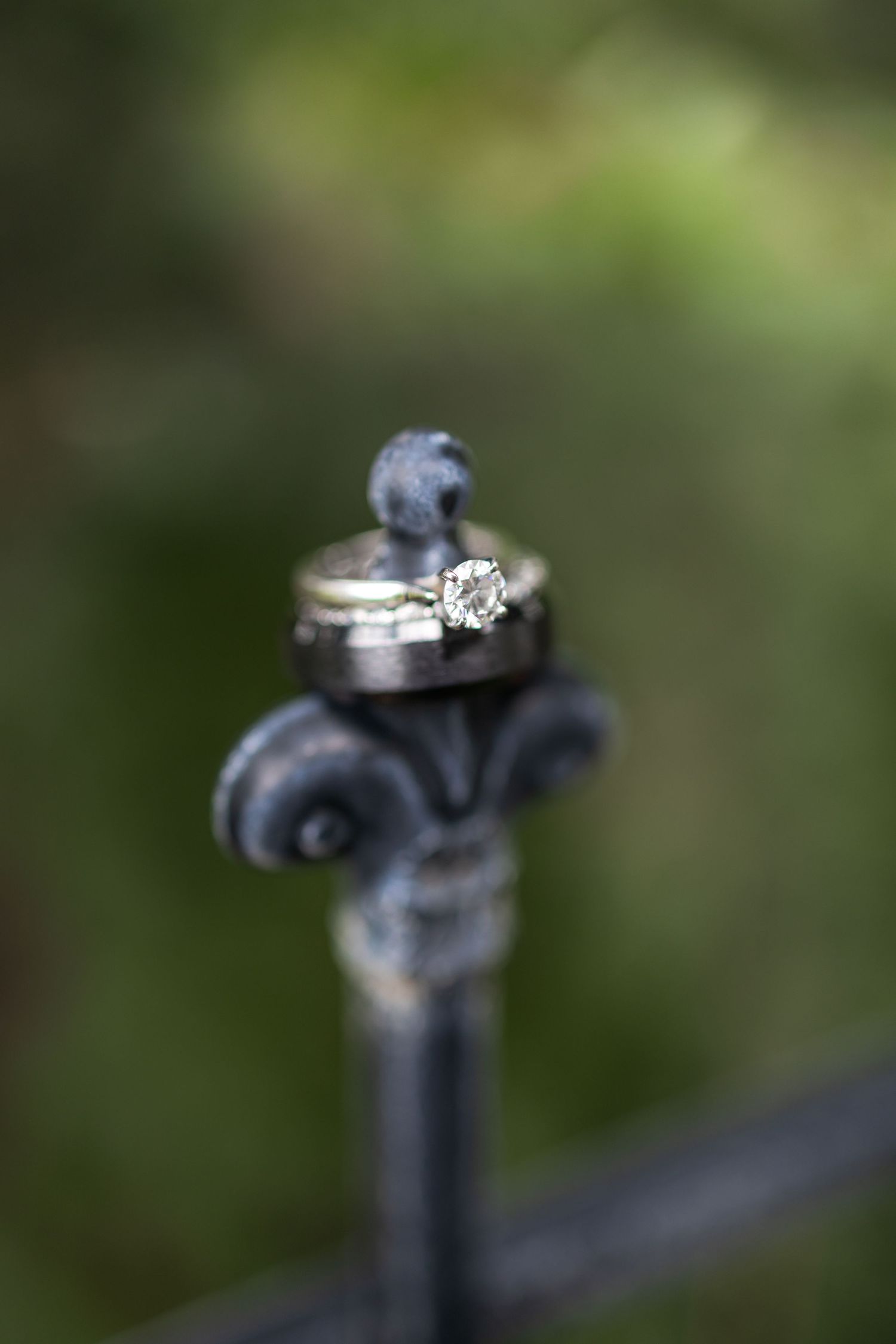 Wedding rings arranged artistically on decorative iron railing with blurred background.