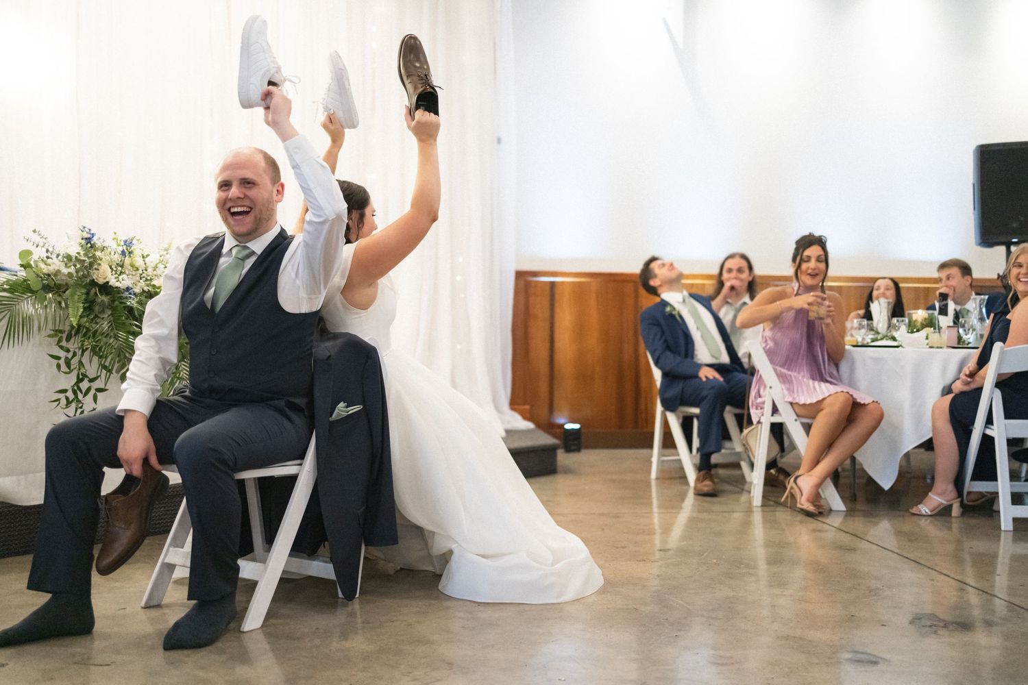 Wedding guests participating in a fun shoe game during the reception with white decor.