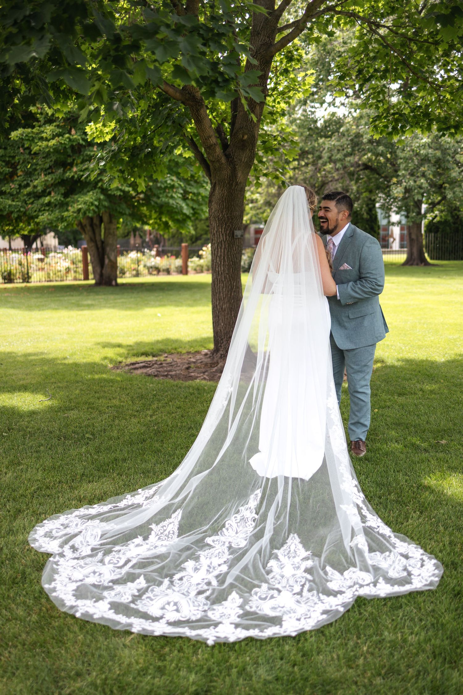 Beautiful wedding dress with long lace train photographed in garden setting.