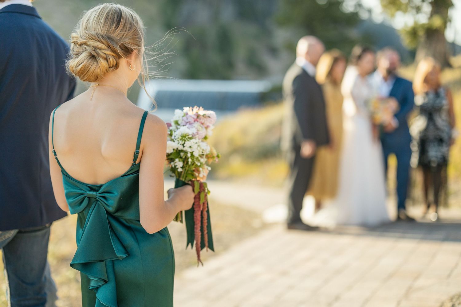 Wedding guests in formal attire walking along a mountain path.