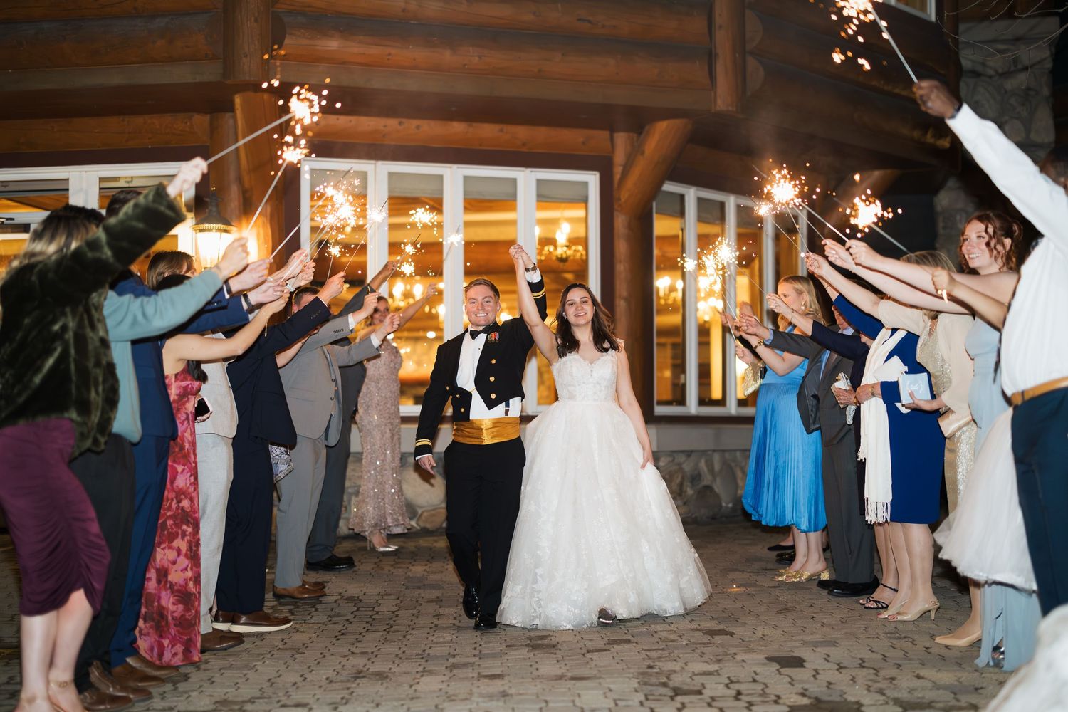 Wedding guests hold sparklers to create a magical light tunnel as newlyweds exit their reception celebration.