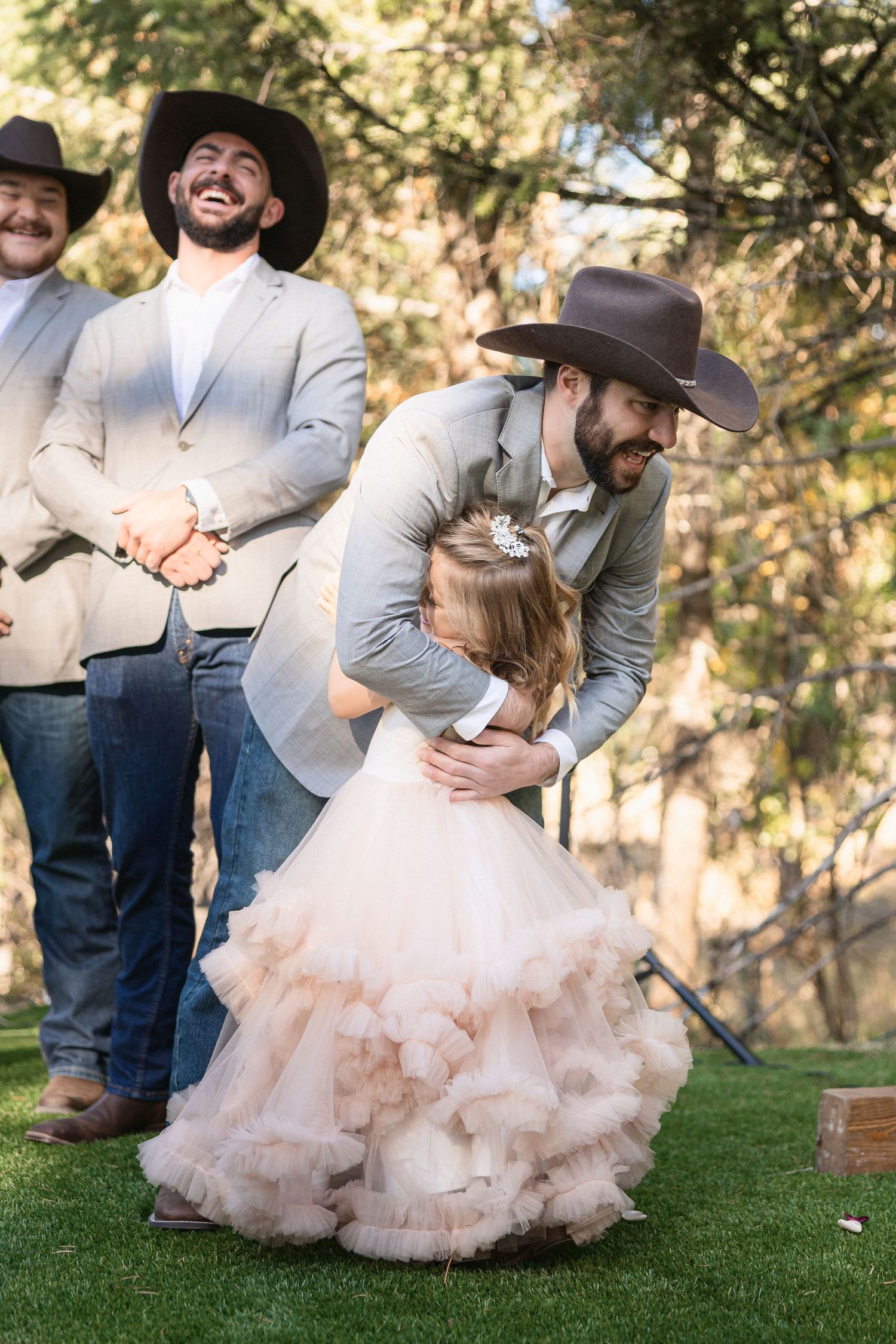 Playful dancing moment captured on grassy lawn at rustic outdoor wedding.