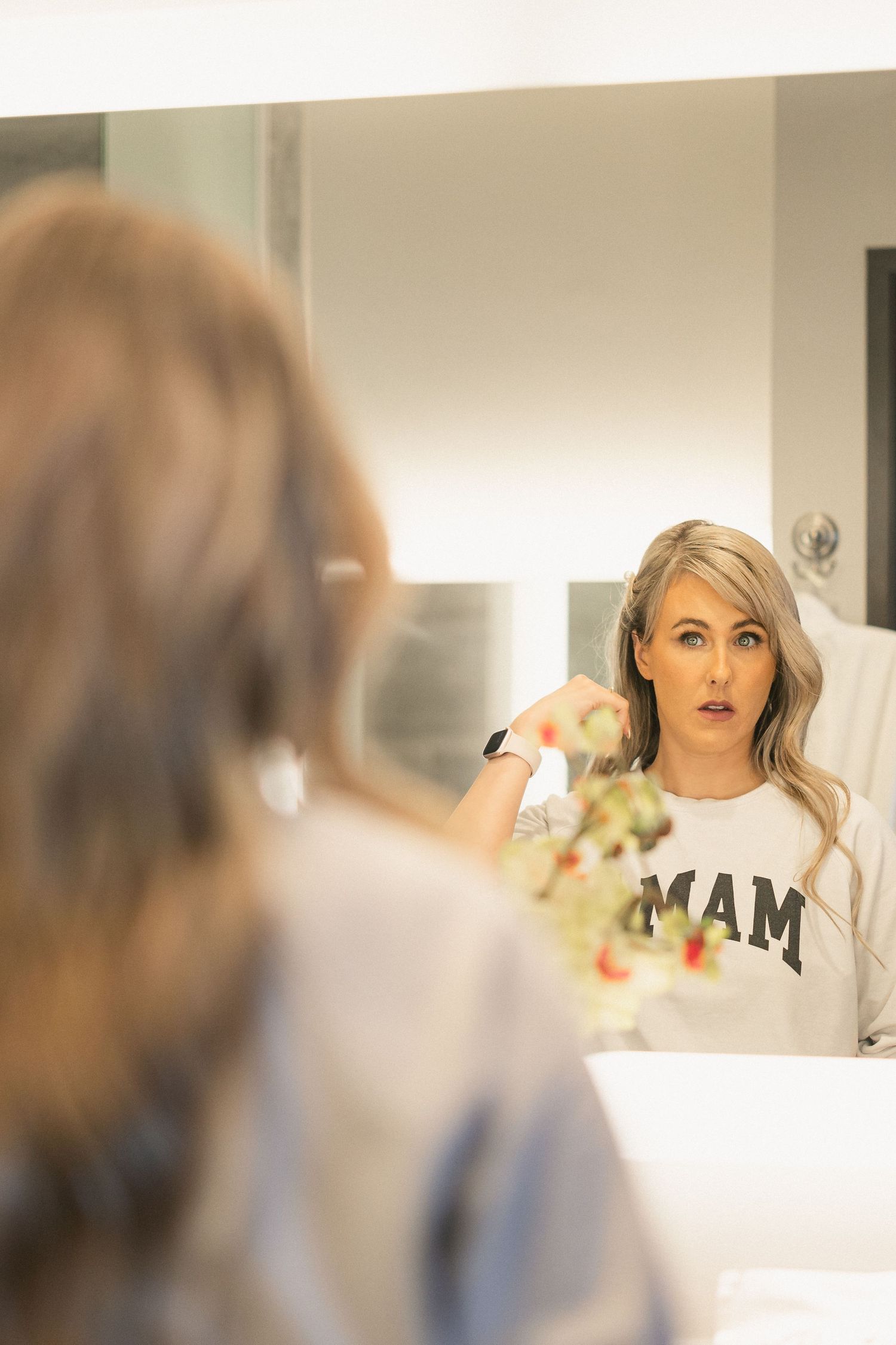 Mirror reflection showing preparation for wedding day while wearing casual shirt.